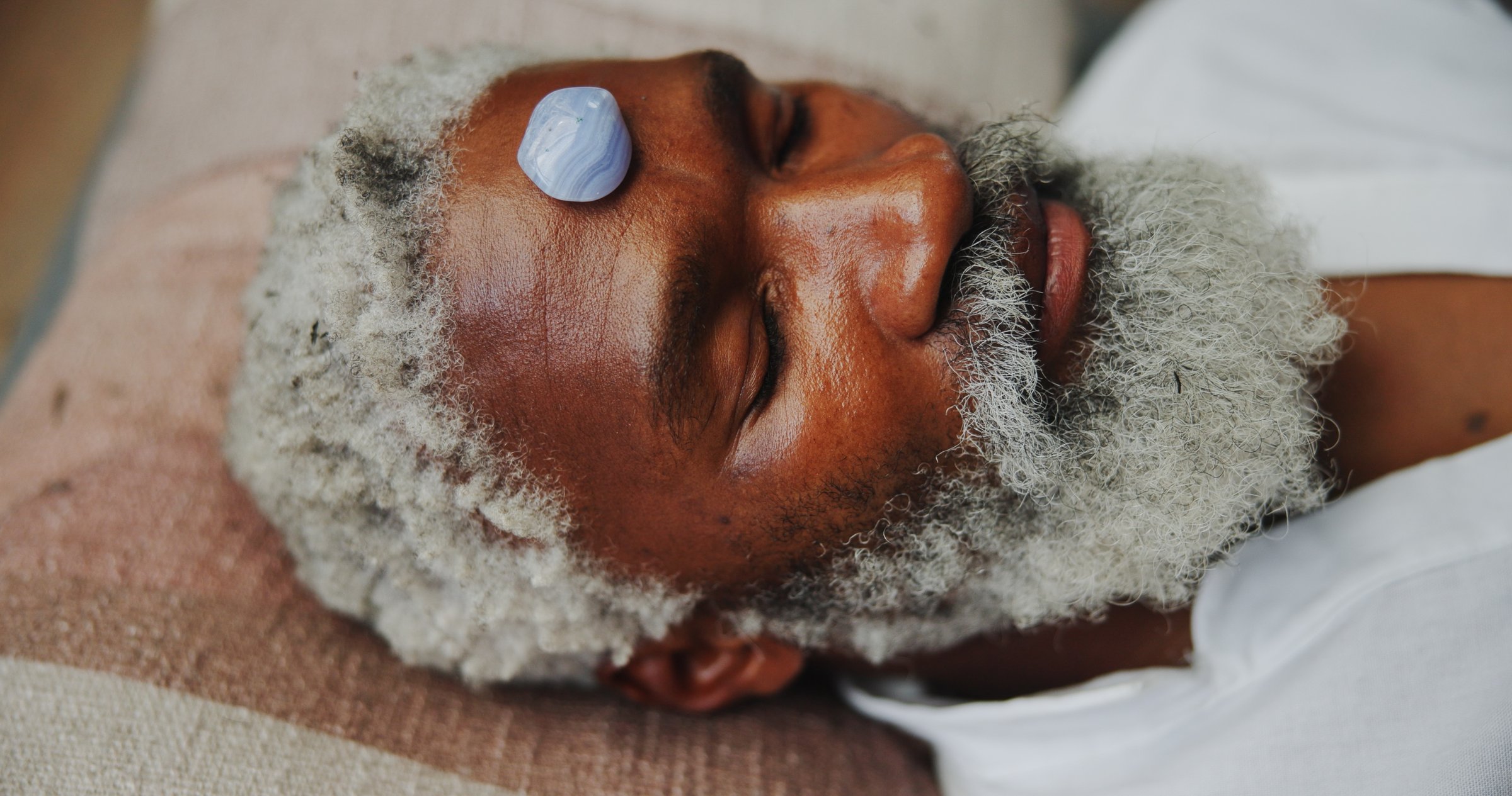Crystal, zen and holistic with black man on floor for energy balance, meditation or spirituality. Third eye chakra, peace or healing with senior person for aura cleanse, mind and wellness ceremony