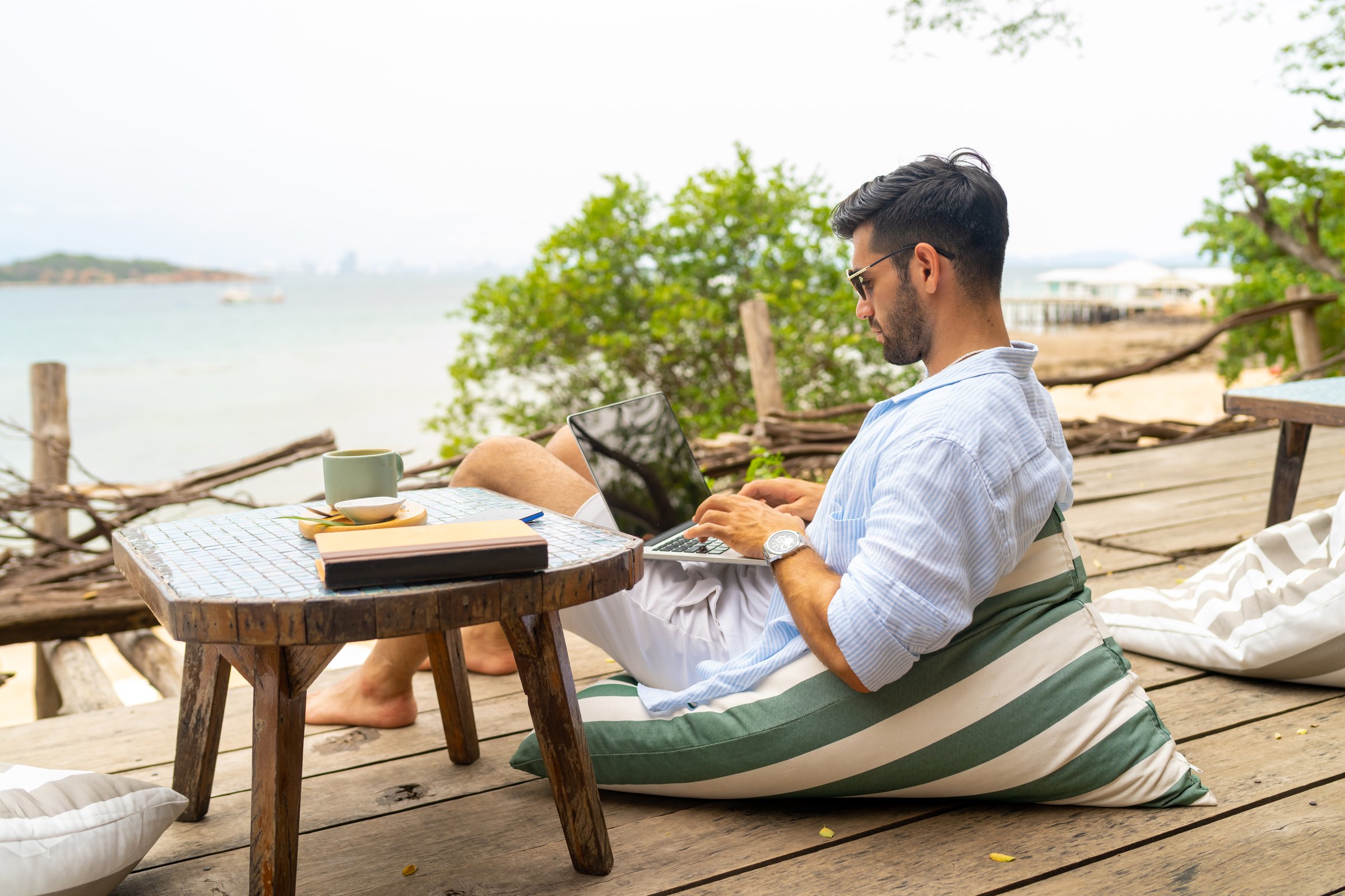 Caucasian businessman remote working online corporate business financial on laptop computer at beach cafe. People enjoy outdoor lifestyle travel tropical island on summer beach holiday vacation.