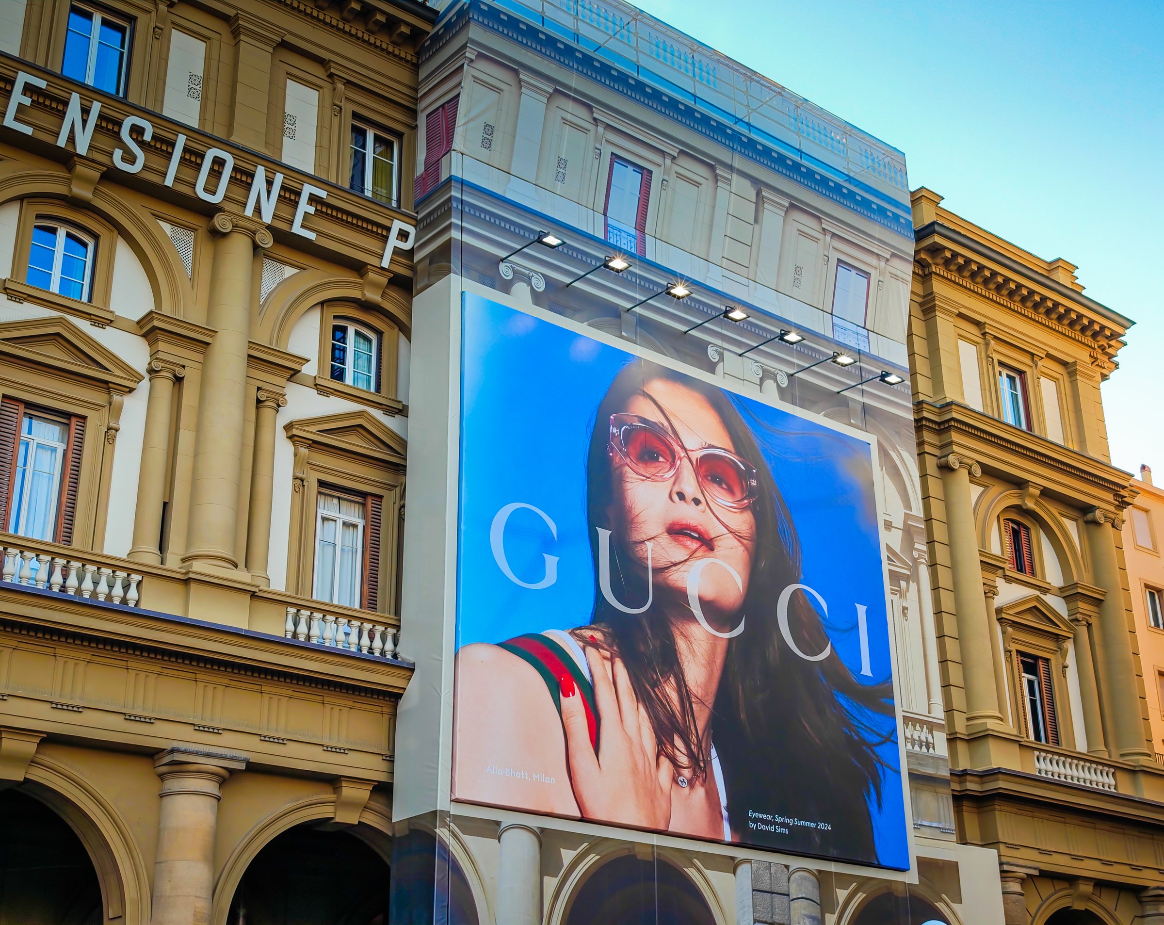 Large advertising billboard for Gucci, a famous Italian luxury brand on the facade of old historical building