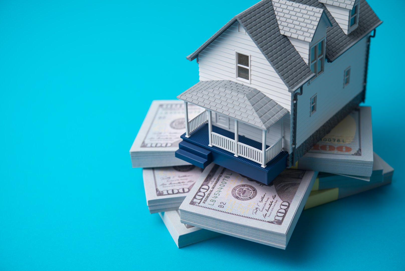 House model on heap US dollar banknotes. Return on investment (ROI) from real estate investment trust (REIT), yield and profit from sales or rentals, reverse mortgage, home for cash and so on concept.