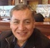 Smiling person wearing a dark jacket seated indoors at a restaurant with a blurred background.