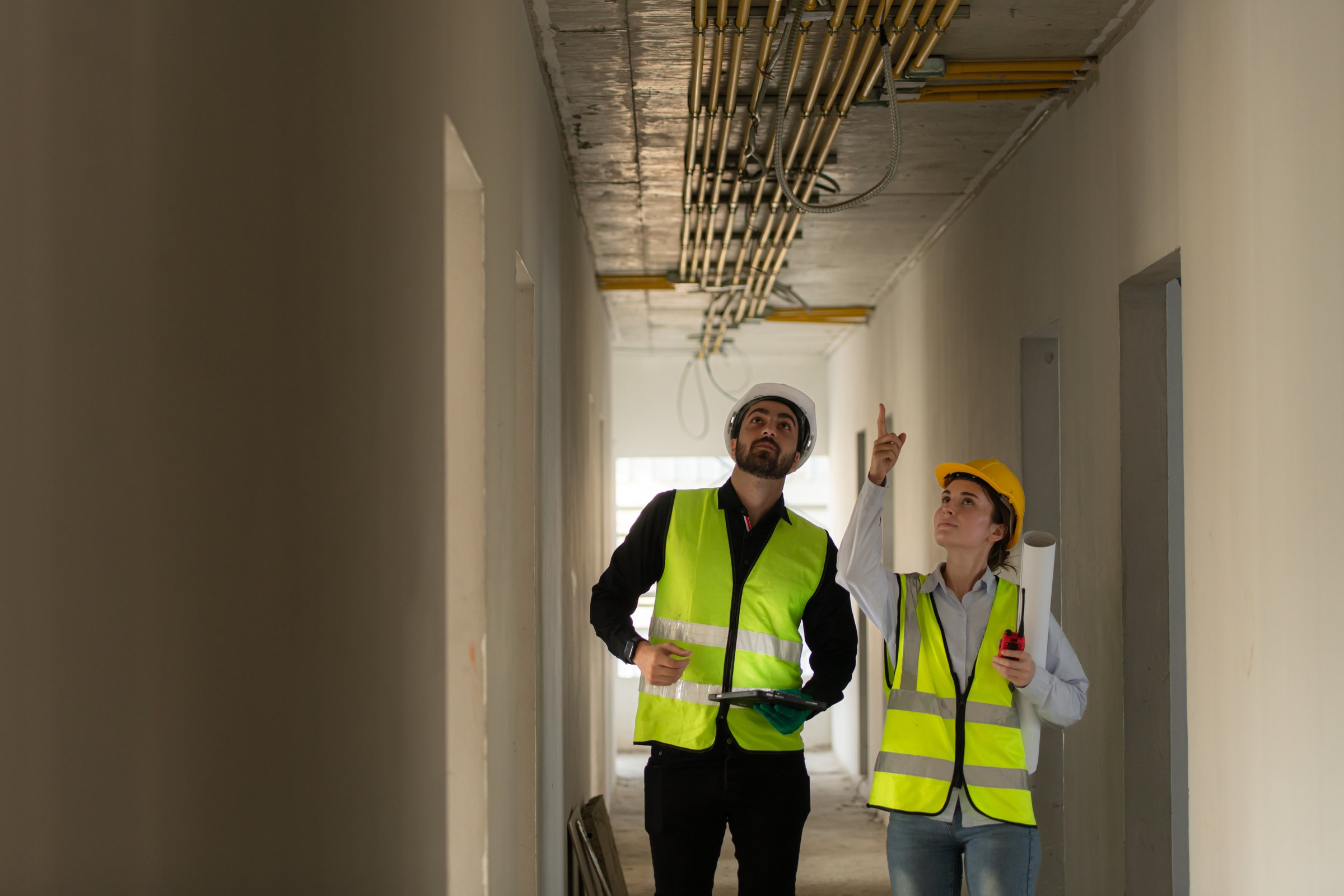 Male and female engineers working on construction site, they are monitoring the building's electrical system.