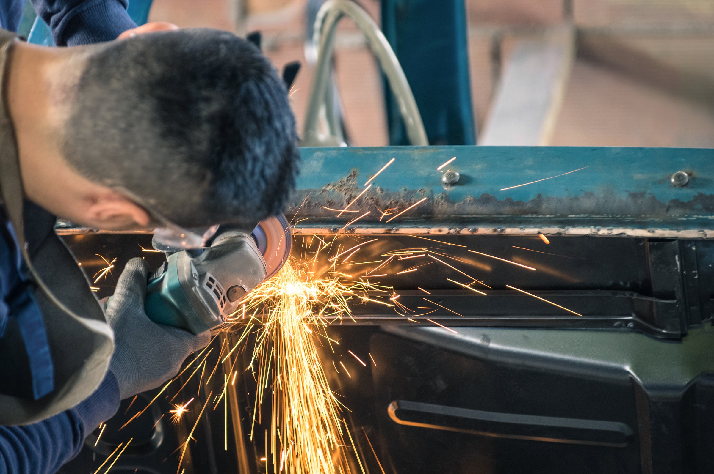 Young man mechanical worker repairing an old vintage car body in messy garage - Safety at work with protection wear