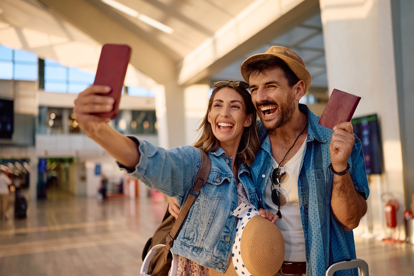 Cheerful couple going on a vacation and taking selfie at the airport.