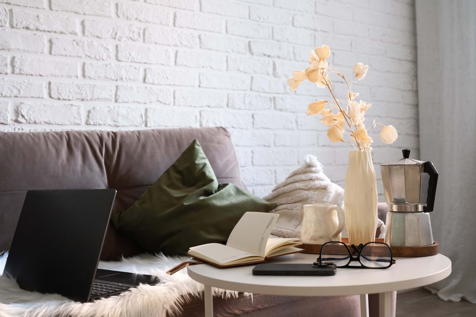 A Stylish and Functional Workspace Featuring a Laptop, mobile phone, notebook with glasses, books in bag on sofa and coffee break. High quality photo