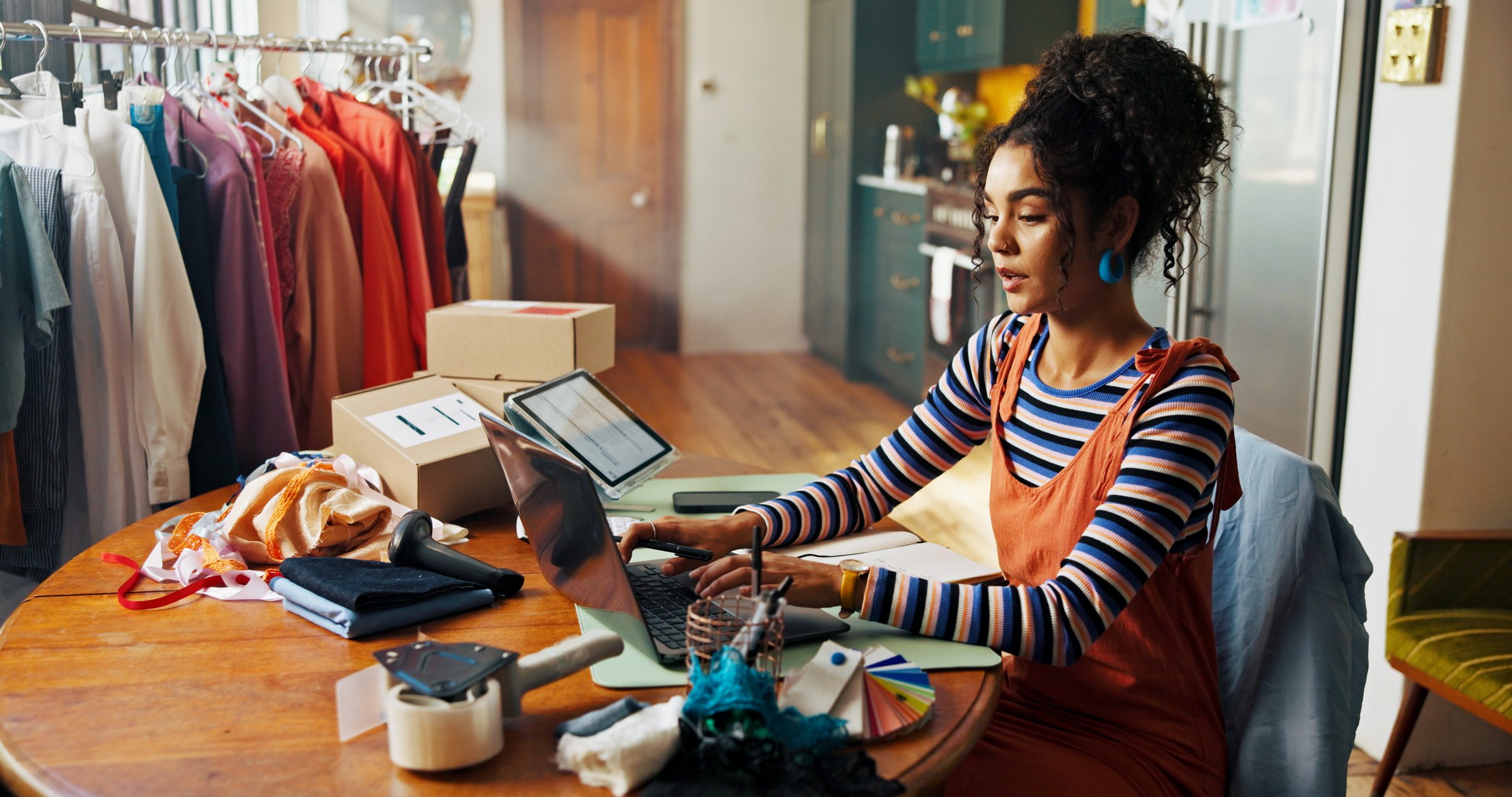 Fashion designer, woman and typing on laptop at small business for fabric order, stock procurement or planning. Entrepreneur, person and tech for shipping schedule, inventory management and delivery