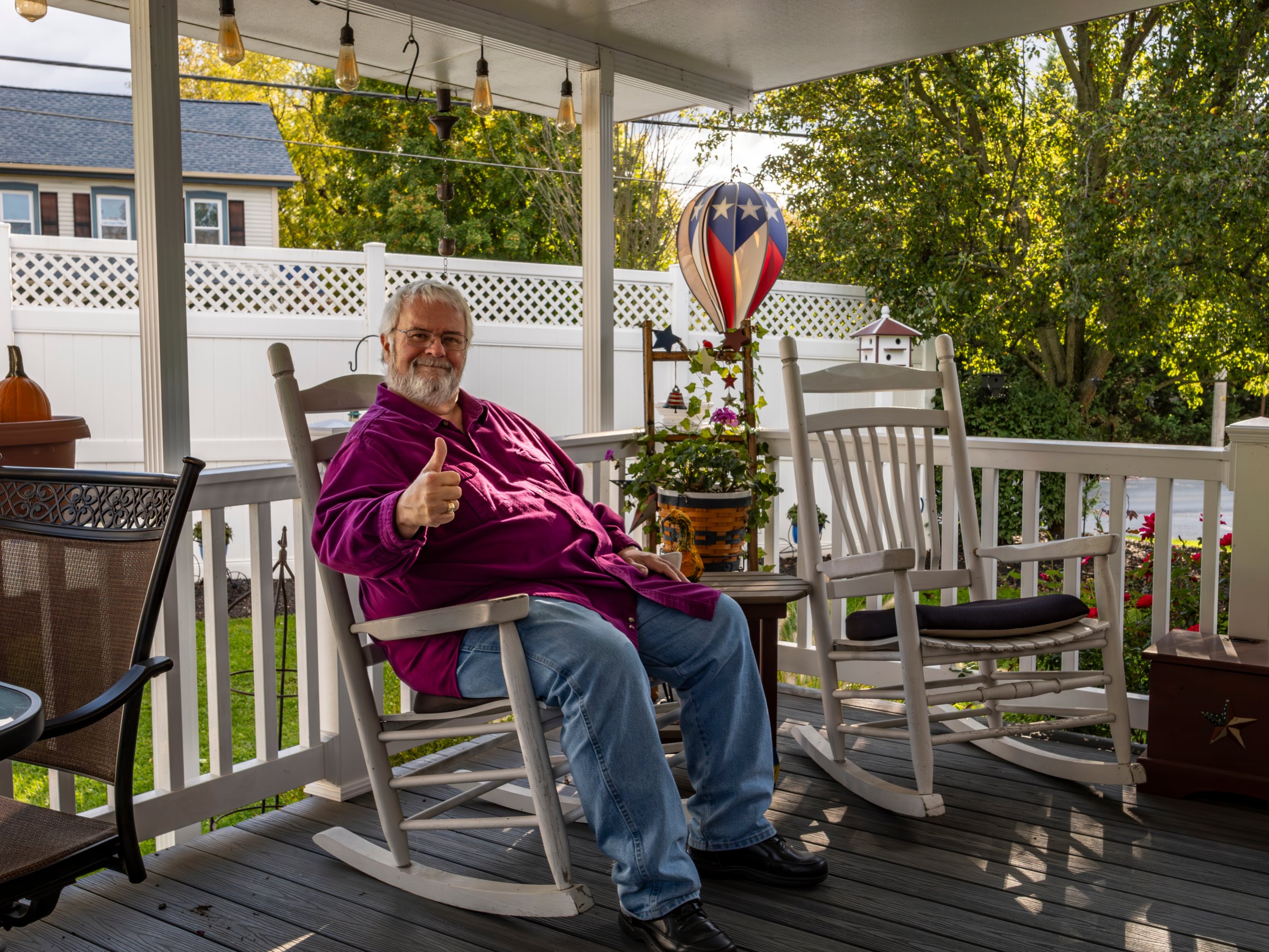 A Senior Aged Male Resting in a Rocking Chair, on a Deck, Enjoying His Retirement and Giving a Thumbs up on a Autumn Day