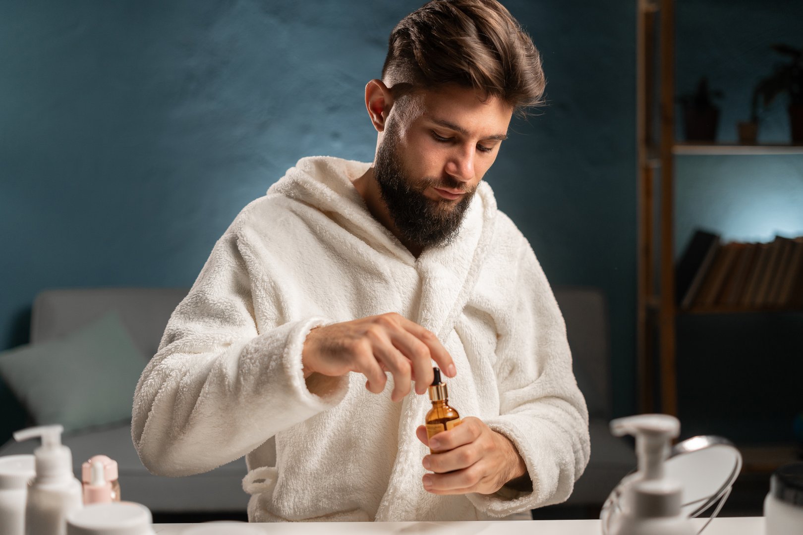 handsome man with pipette with beard oil in living room at home. Copy space