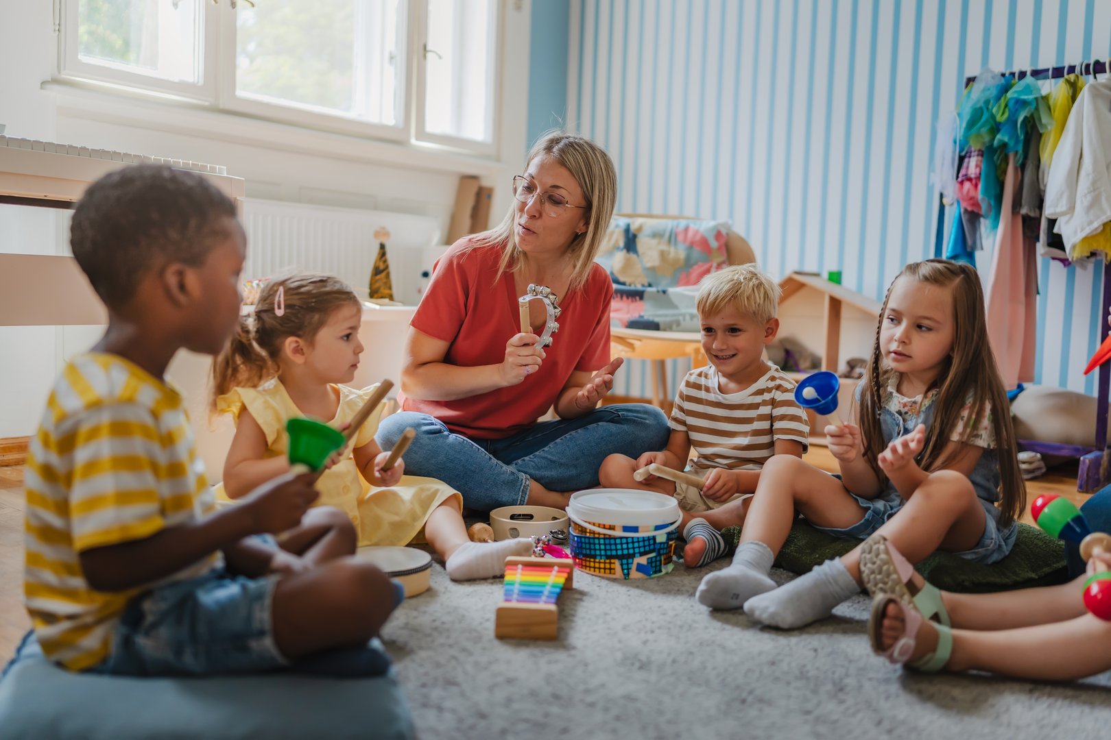 Preschool teacher with young children playing musical instruments in classroom