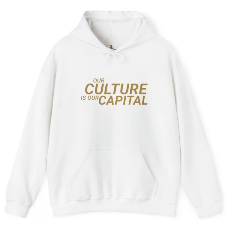 White hoodie with the text Our Culture Is Our Capital in gold lettering on the front.