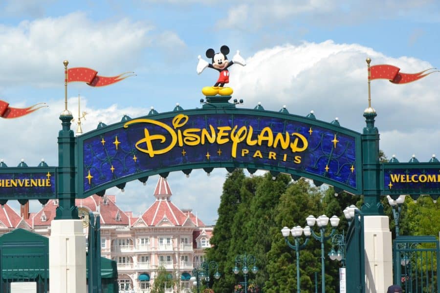Entrance gate to Disneyland Paris with a Mickey Mouse statue on top and the Disneyland Hotel in the background.
