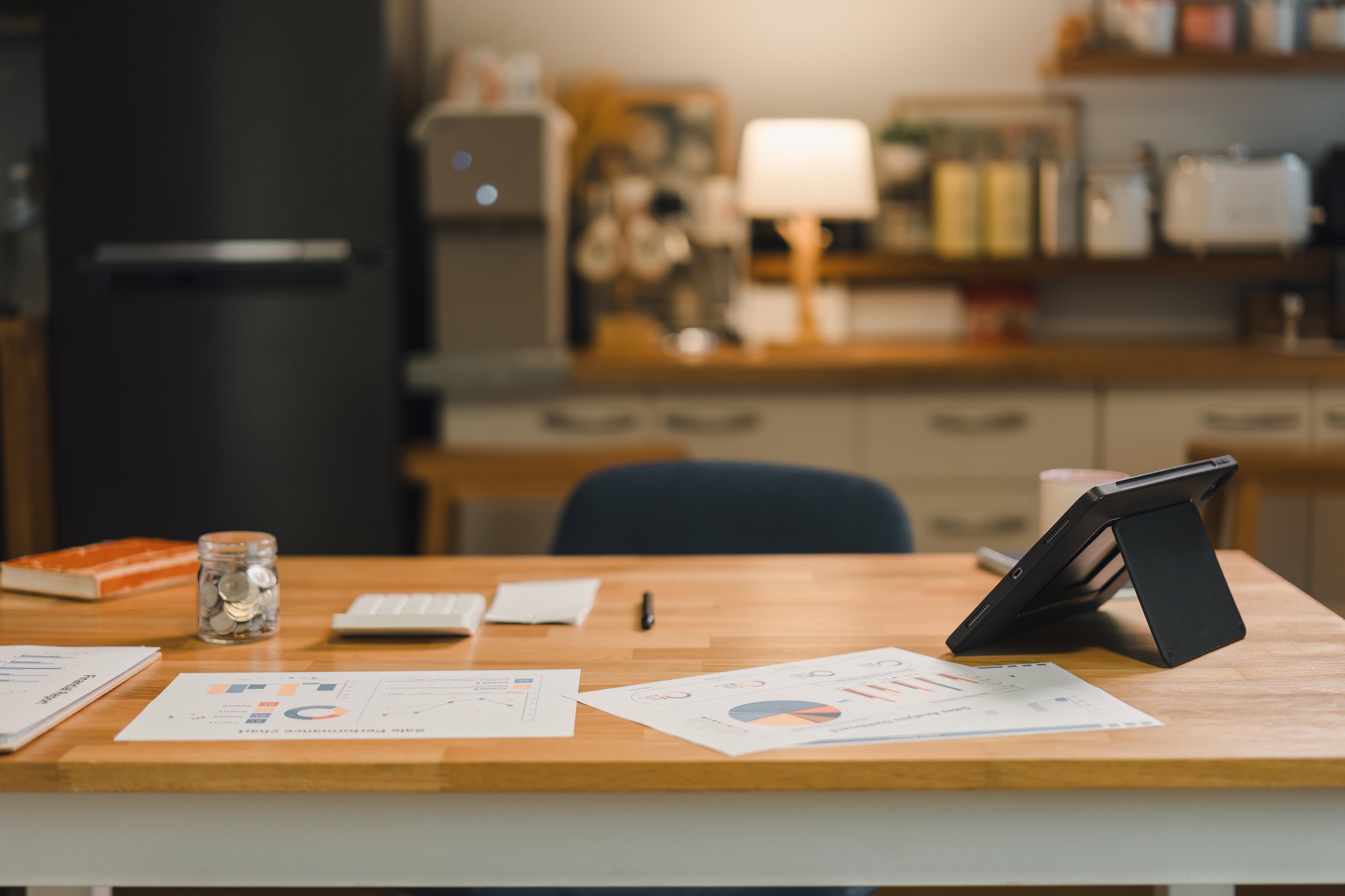 Modern office workspace featuring documents tablet and calculator on wooden table ideal for finance and productivity themes.