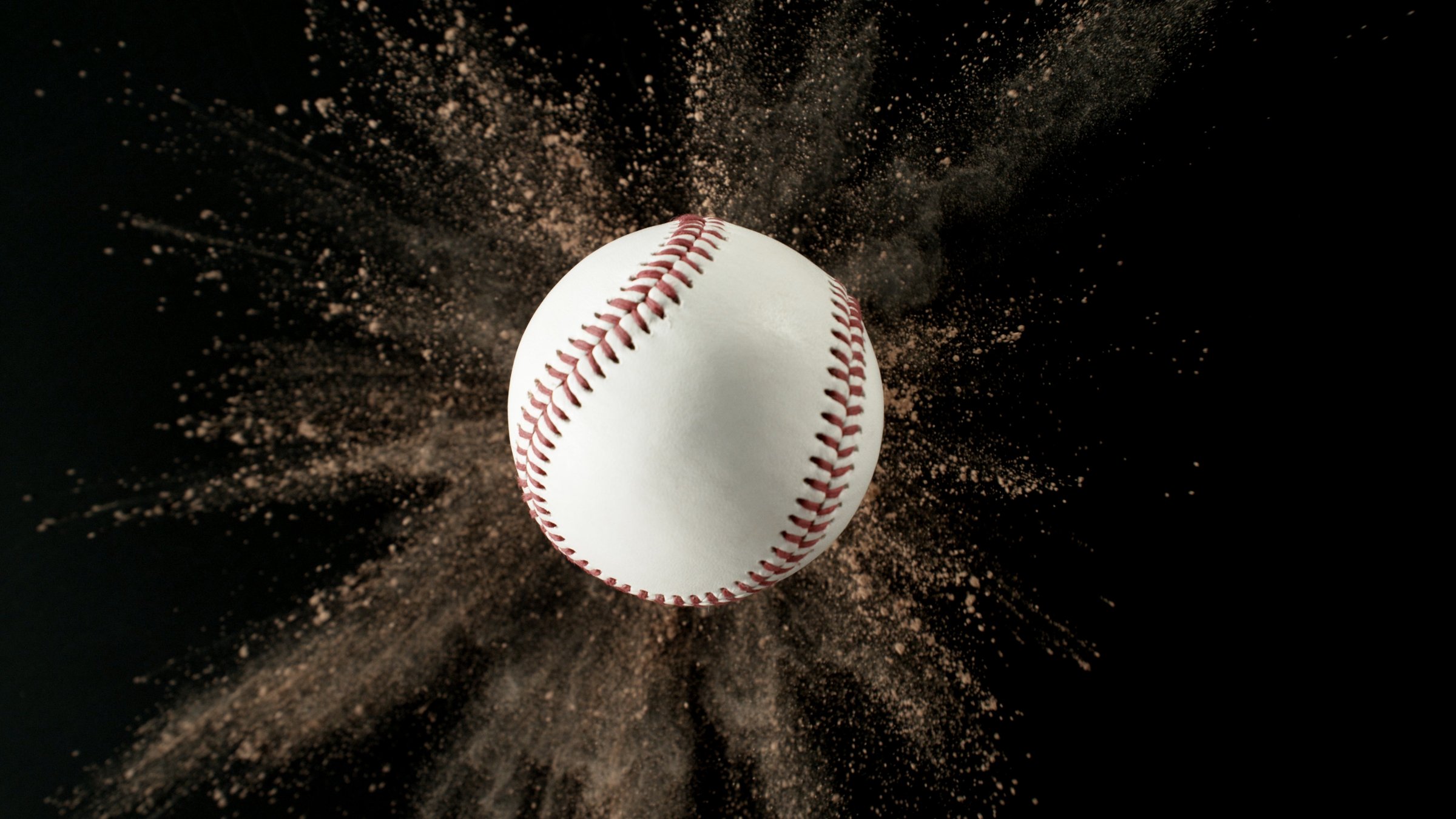 Baseball ball with coloured powder explosion. Isolated on black background.