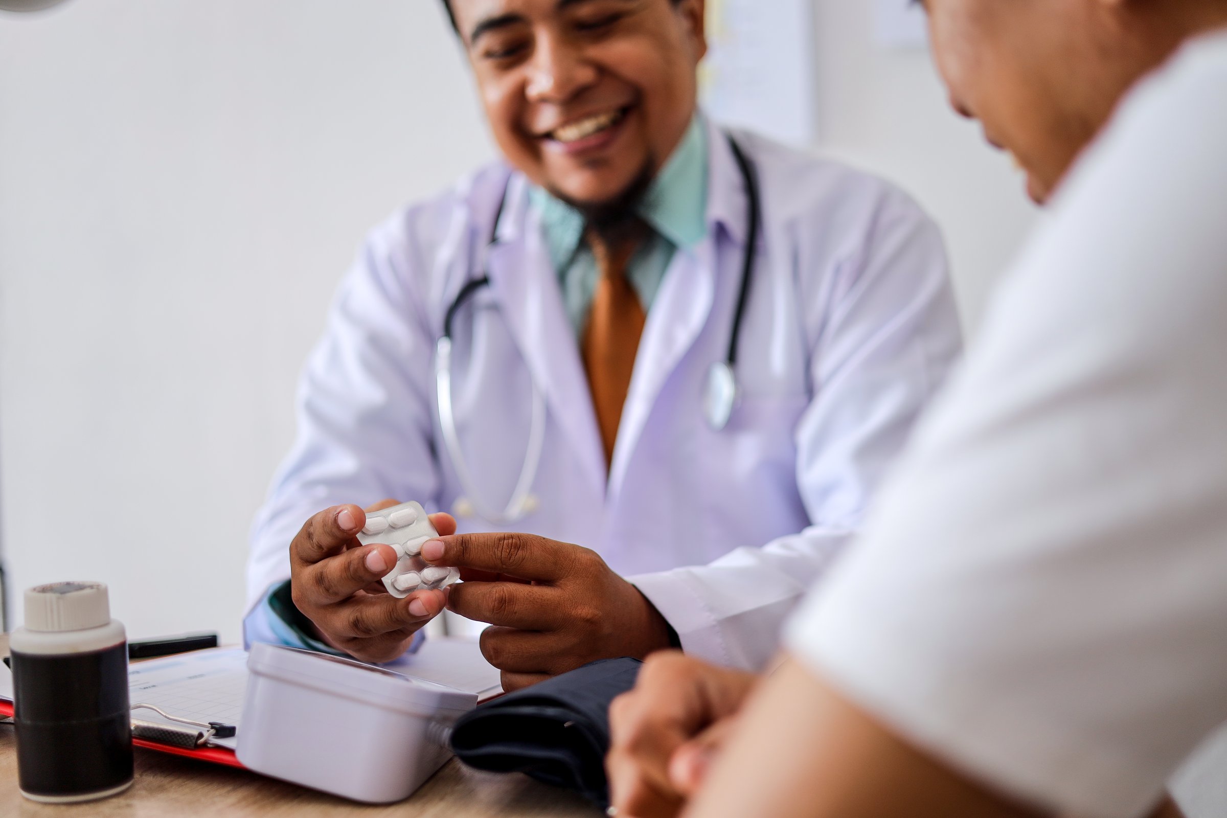 Male Doctor Prescribing Medications to Patient After Check Up in Clinic