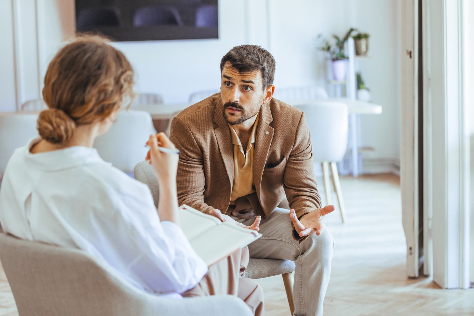 Focused discussion at a consultation between a professional therapist and a client in a modern, bright office. Vibrant exchange showcasing support, understanding, guidance, and verbal communication.