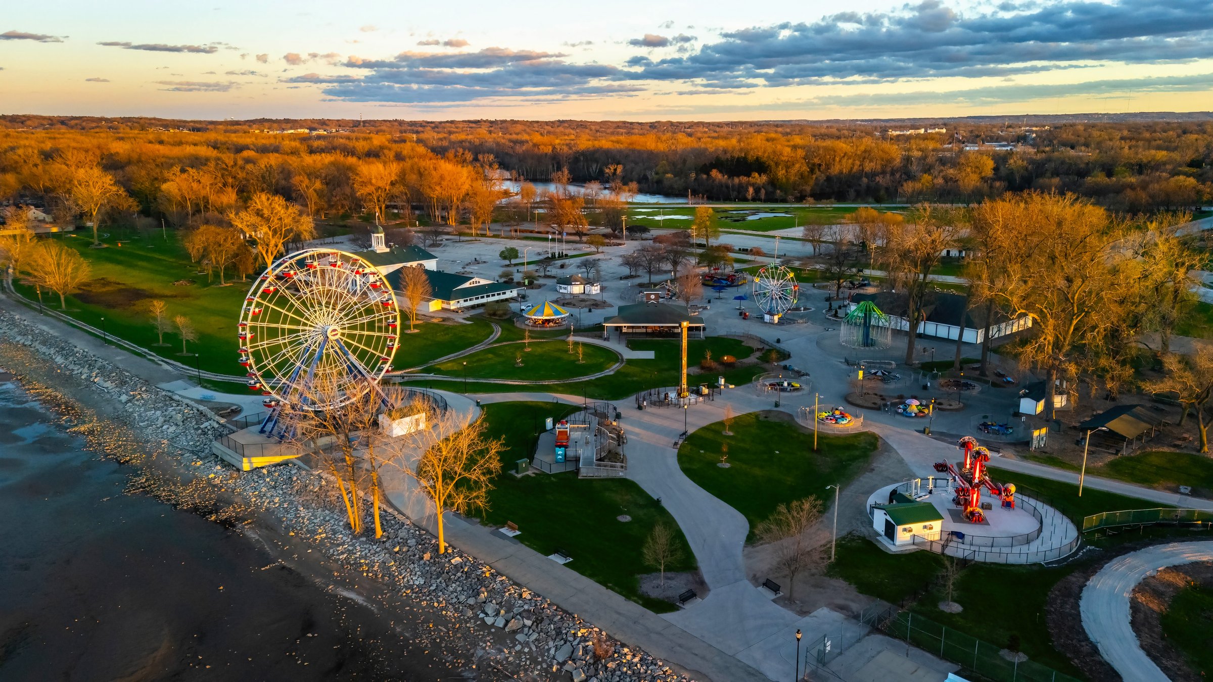 View of the Ferris wheel at Bay Beach Amusement Park in Green Bay Wisconsin during sunset, with golden sky and lakefront in the background.