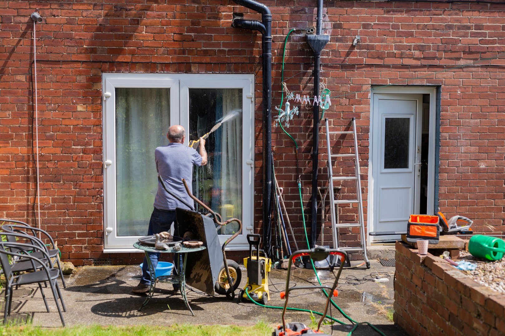 Man using a pressure washer to clean windows
