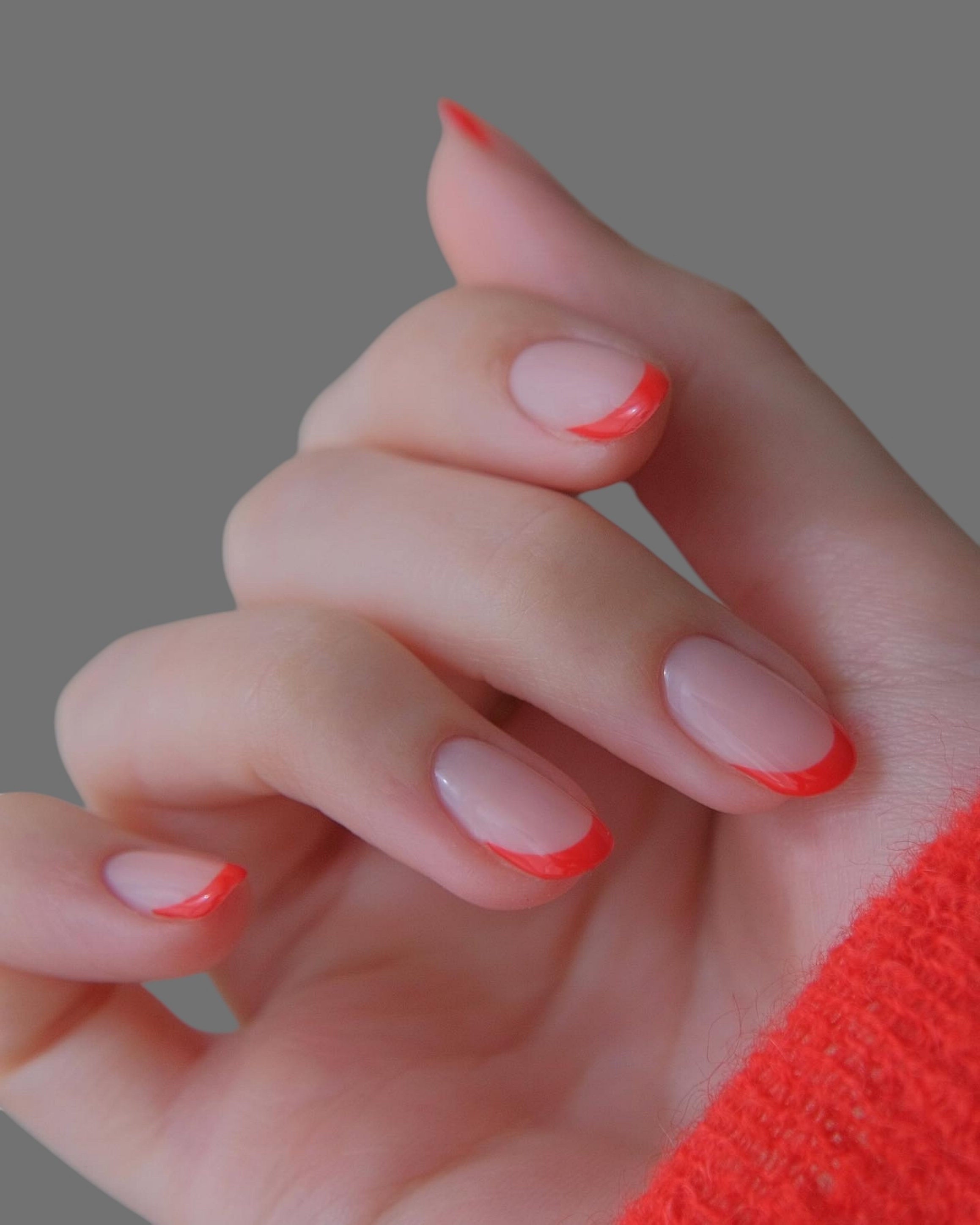 Young woman's hands with innovative, modern, hand-painted red nail manicure with different shapes and designs with light background _ Modern nail manicure design