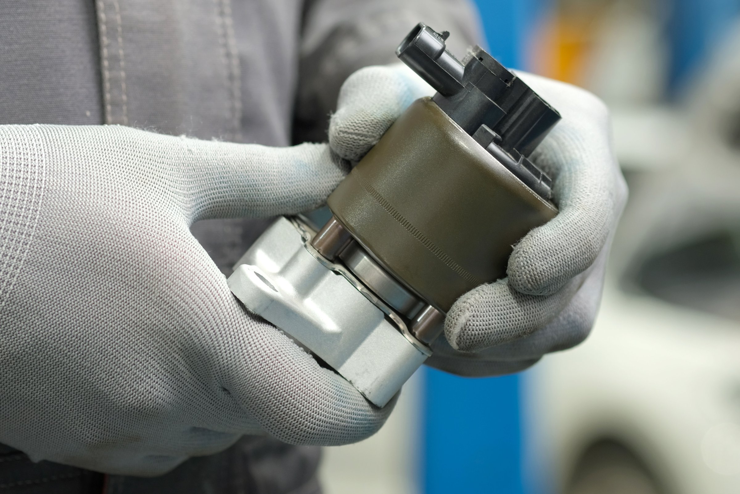 An auto mechanic holds a new spare part in his hands. Visual inspection of the integrity and serviceability of the product before replacement.