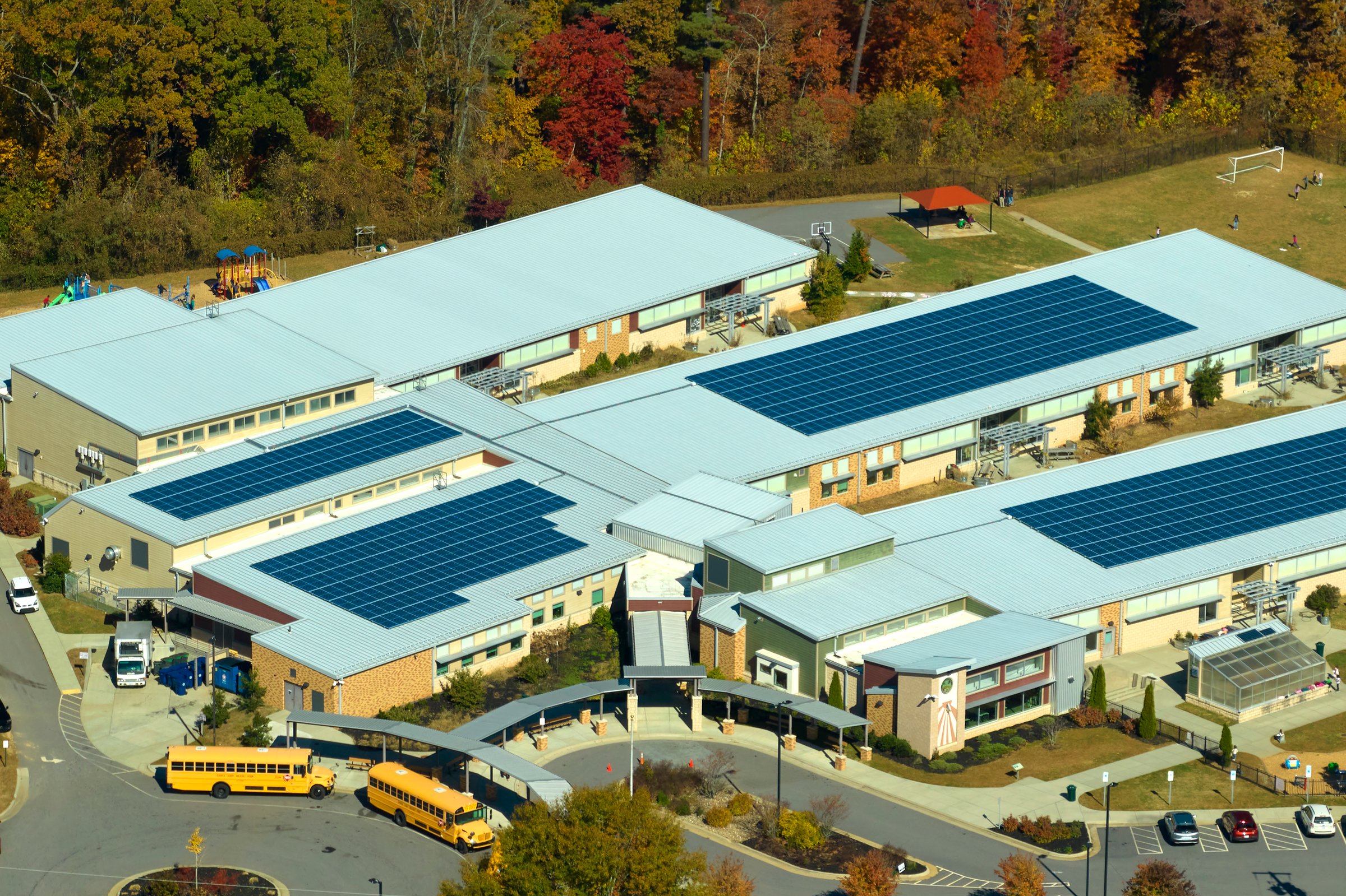 Aerial view of american school building with rooftop covered with photovoltaic solar panels for production of electric energy.