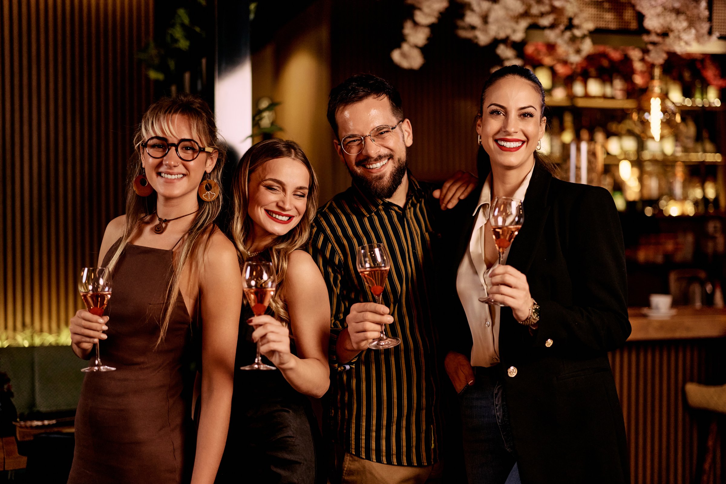 A group of friends toasting and smiling in a vibrant and cozy bar.
