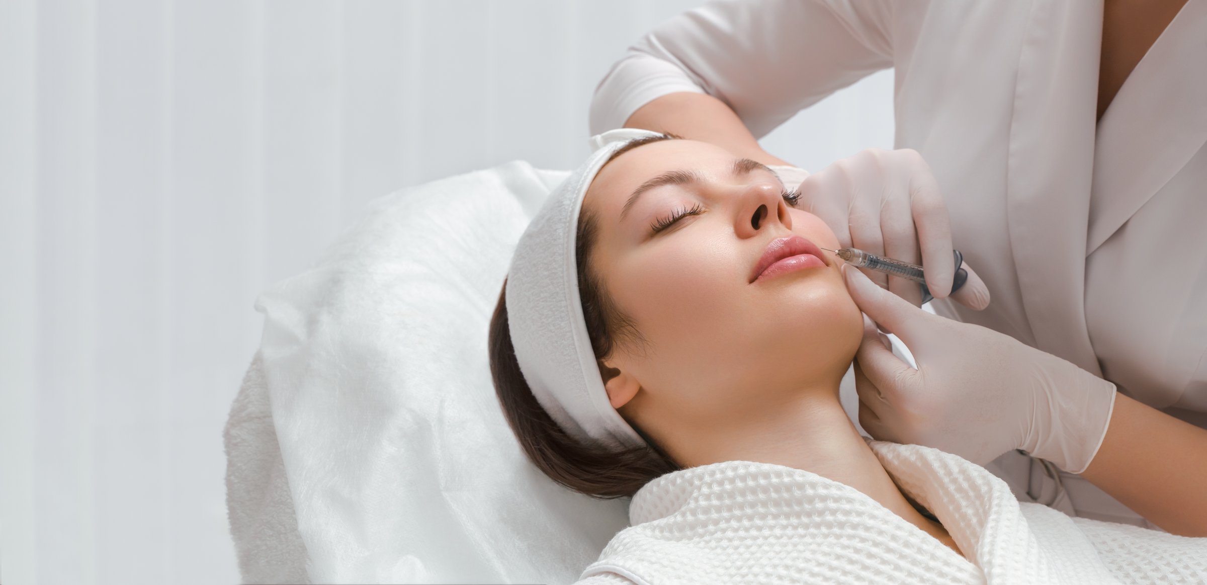 Lip augmentation and correction procedure in a cosmetology salon. The specialist makes an injection in the patient's lips
