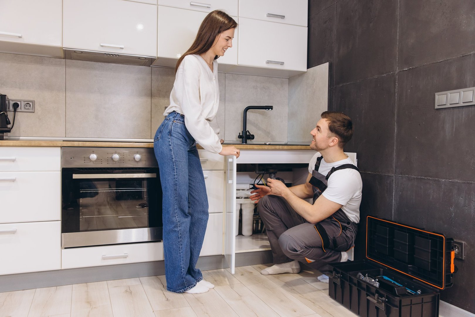 Plumber explaining the operation of a water filter to a customer in a modern kitchen, showcasing expertise and providing valuable guidance