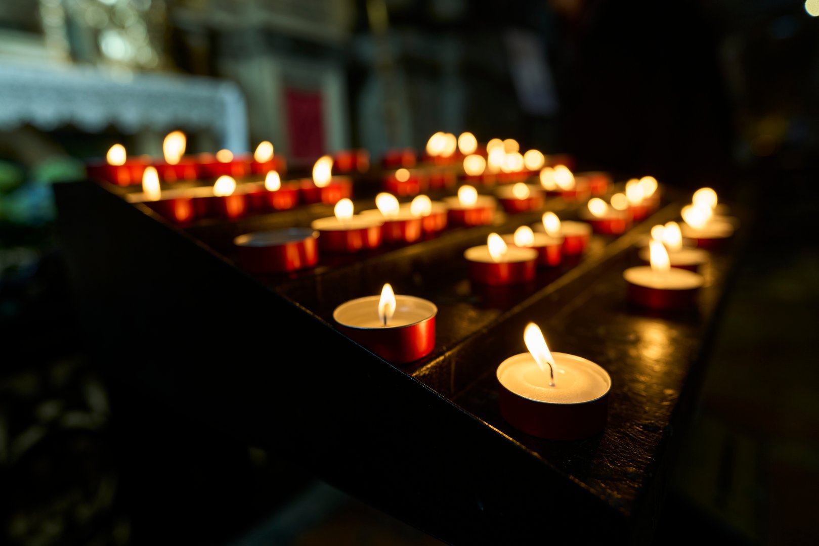 A row of lit candles in a dimly lit church creating a serene and spiritual atmosphere.