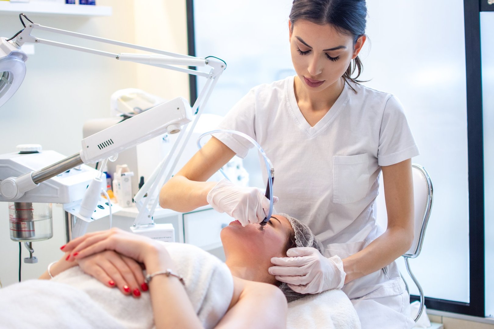 Young woman receiving hydra-facial therapy at beauty salon