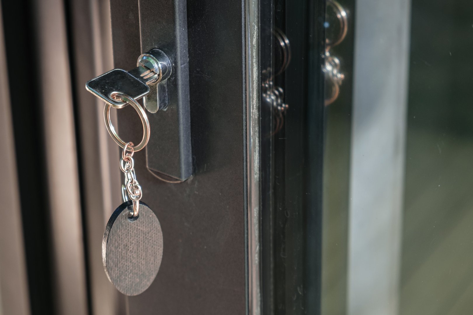 Key with a large oval keychain is inserted into the keyhole. The concept of buying residential real estate, space for text.