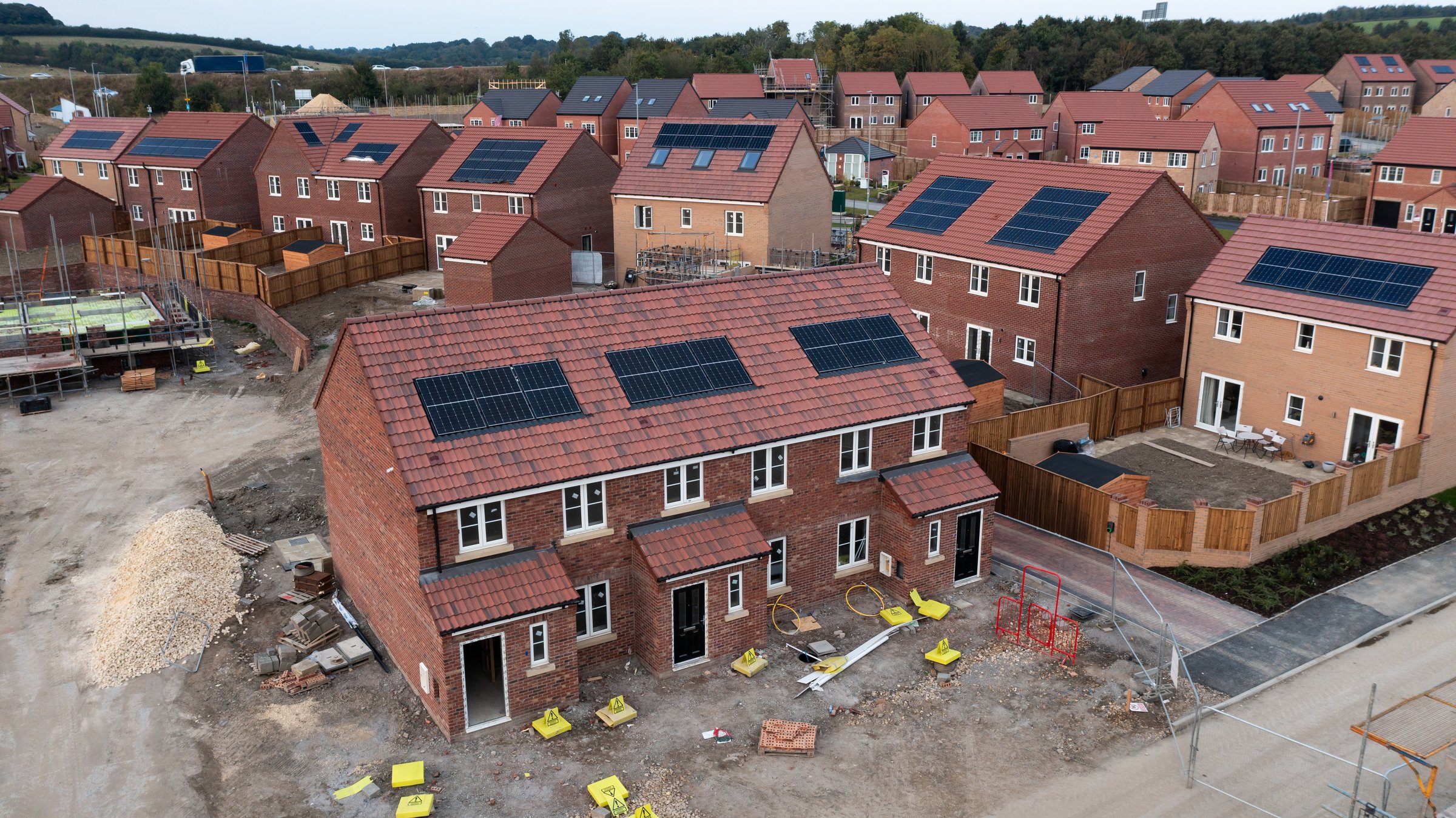 The roof of a row of new build houses on a construction site under construction with roof integrated or In-Roof solar panels for cheap and sustainable energy in an eco friendly property