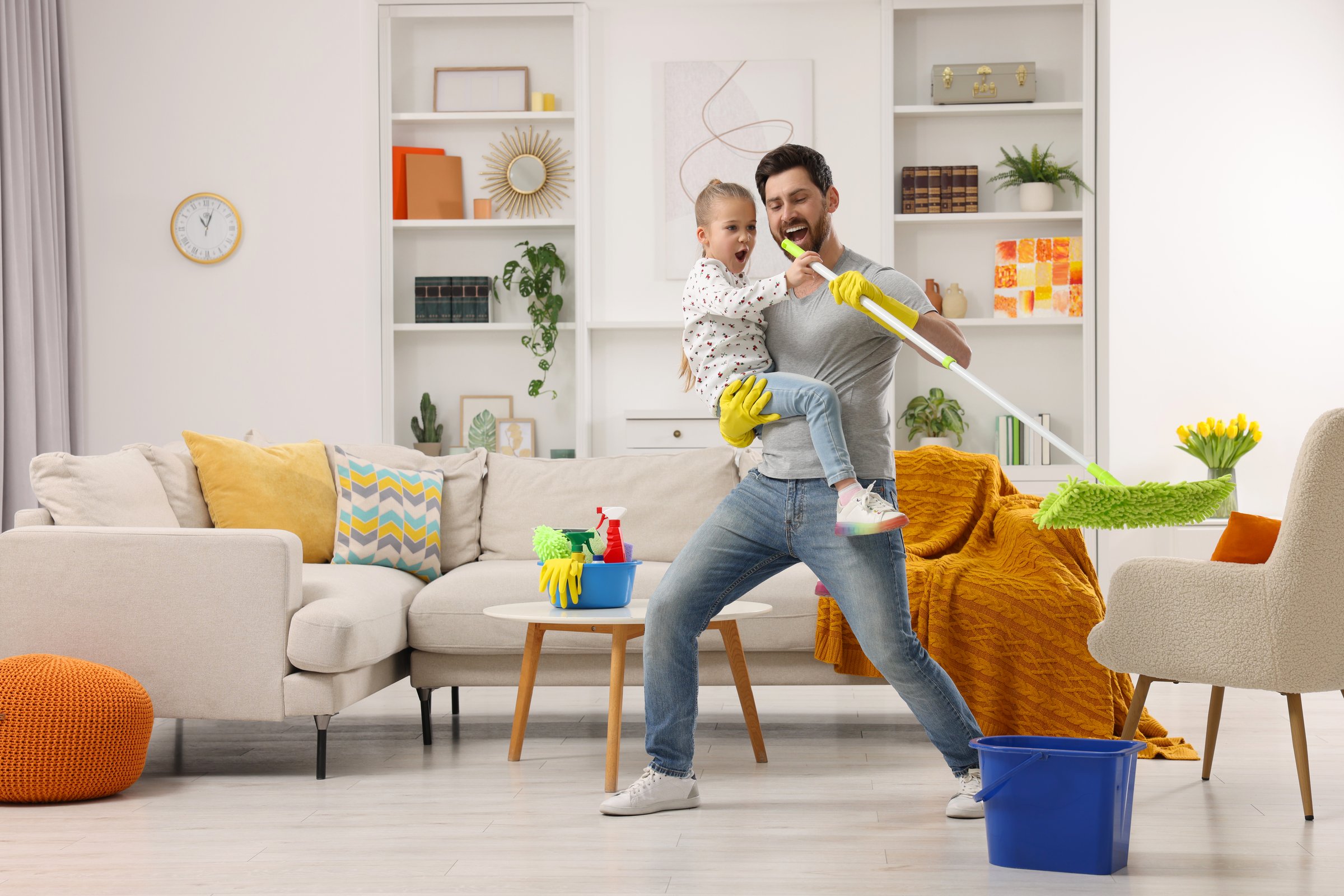 Spring cleaning. Father and daughter singing while tidying up together at home