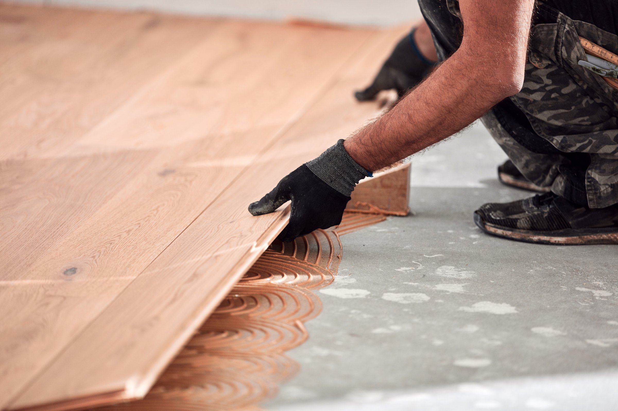 Professional handyman installing laminate flooring in a new apartment.