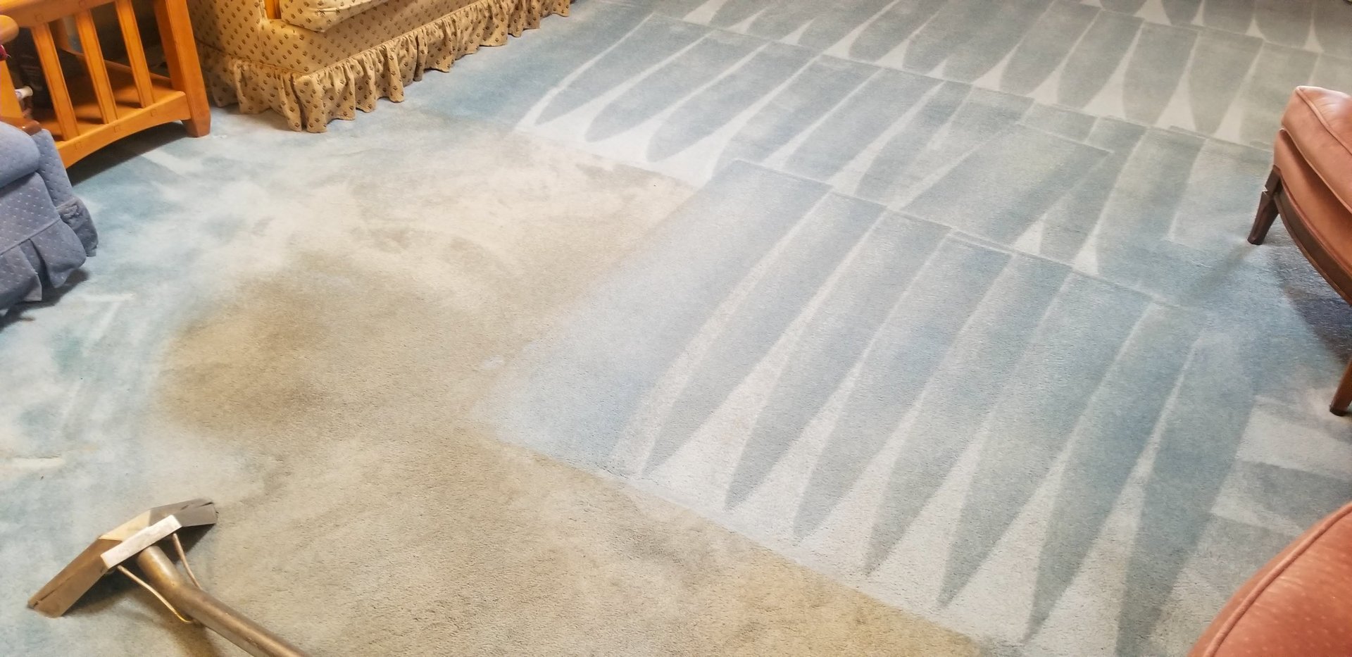 A living room carpet undergoing deep cleaning, with clear before-and-after contrast. The left side shows soiled and worn areas, while the right side reveals refreshed, professionally cleaned sections. The cleaning wand and surrounding furniture emphasize the transformation process, ideal for showcasing residential cleaning services or carpet care solutions.