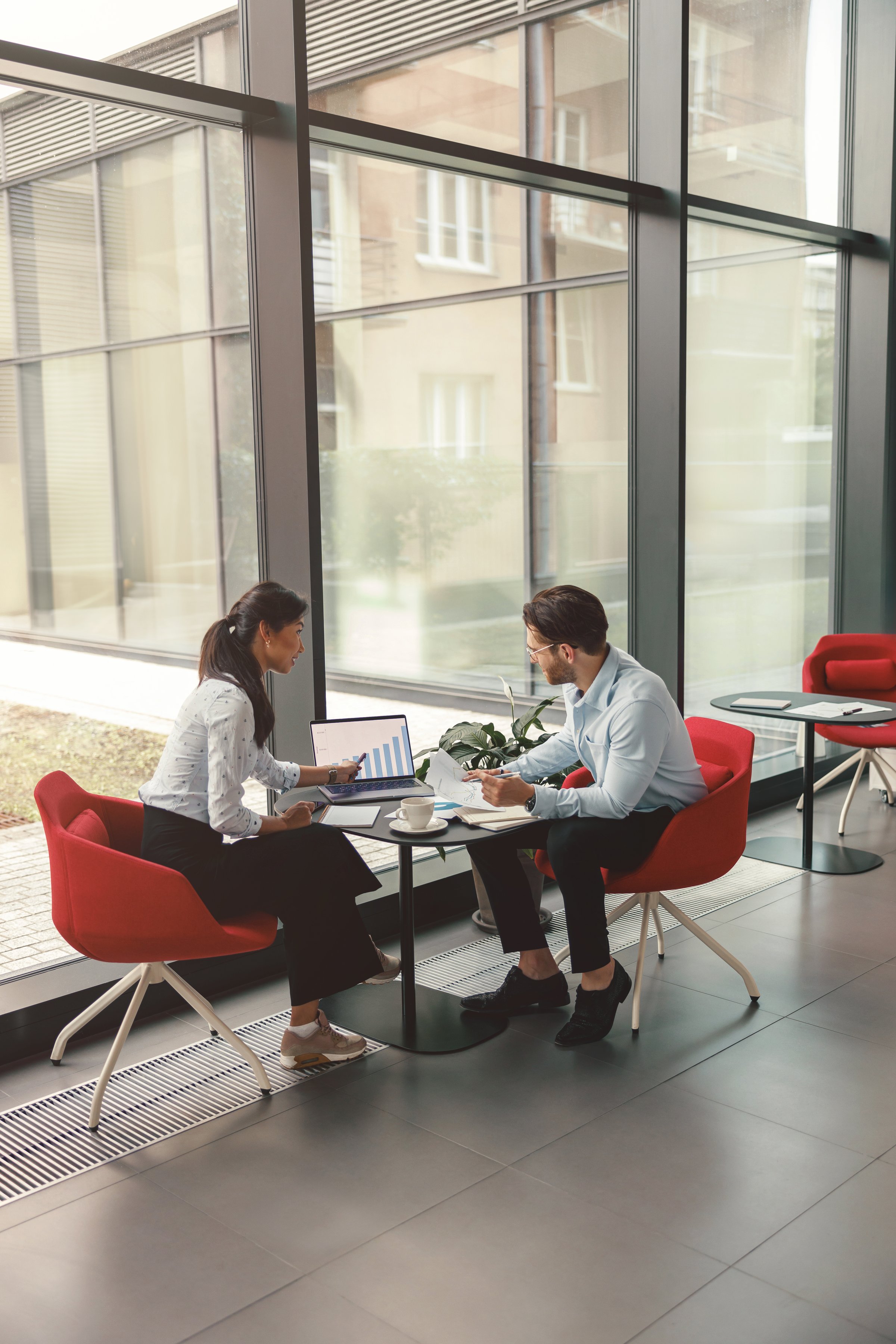 Two coworkers working together on project while using laptop in office meeting room