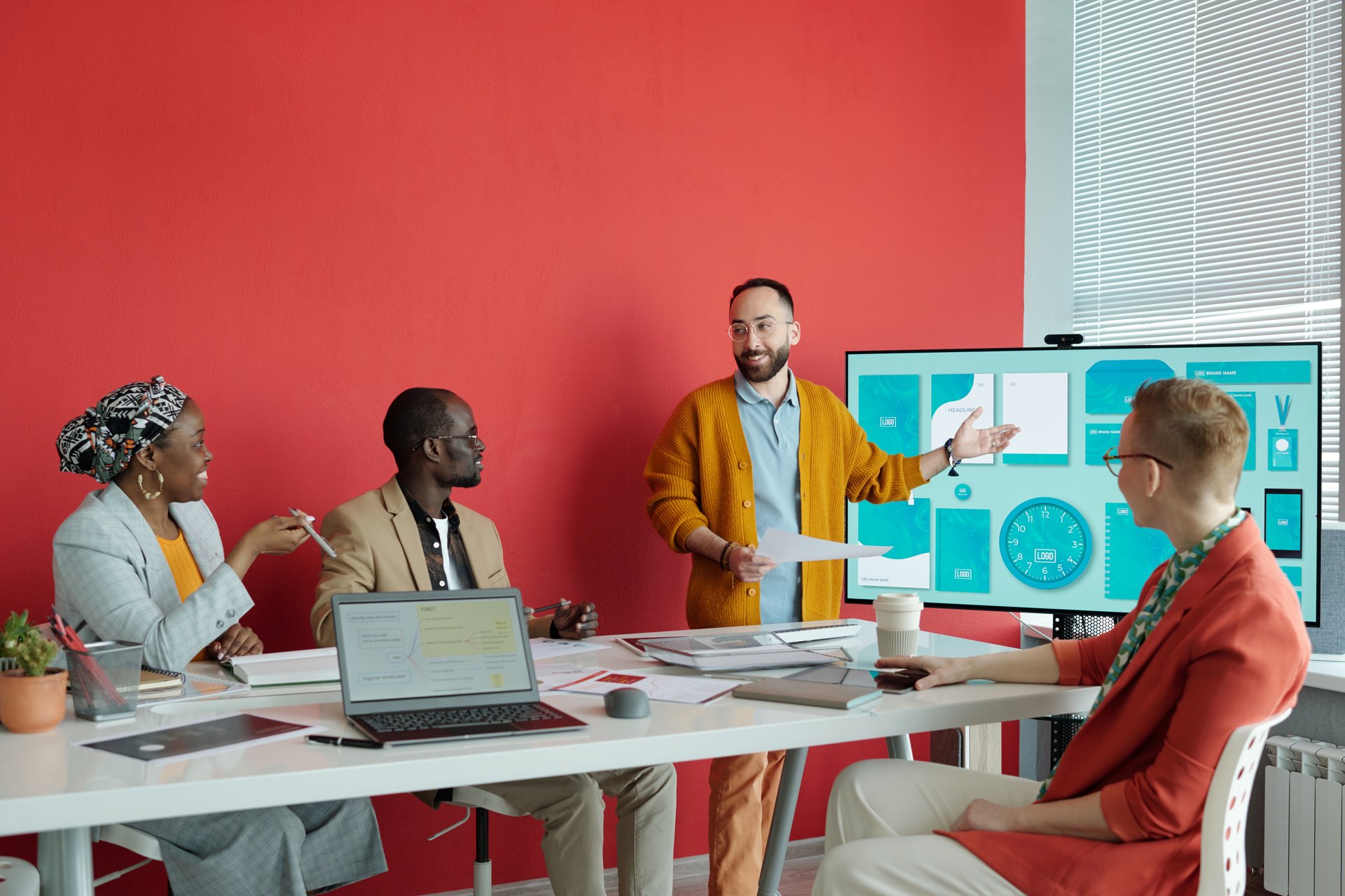 Caucasian businessman explaining presentation on large screen to diverse team of colleagues during office meeting