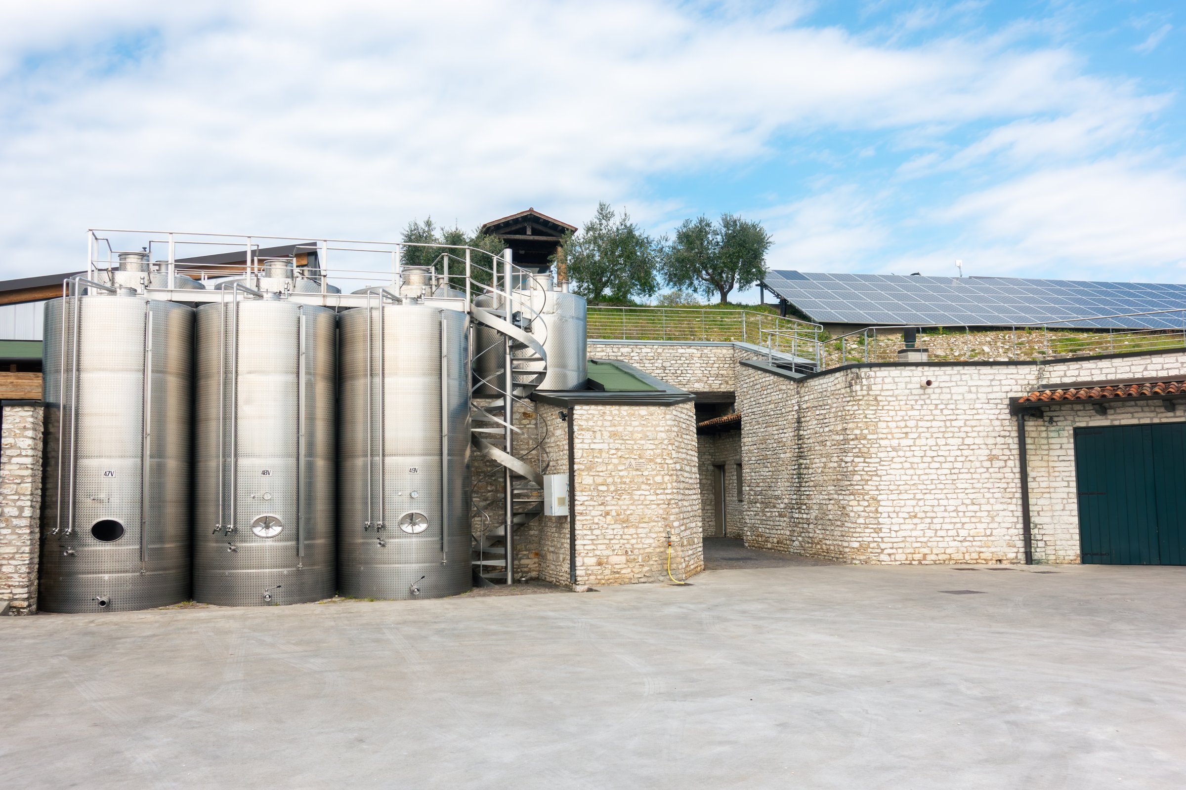 Courtyard of modern sustainable winery and vineyard with steel fermentation tanks and solar panels on the roof for responsible wine making and production