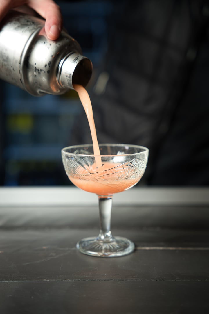 Bartender carefully pouring a freshly mixed pink cocktail