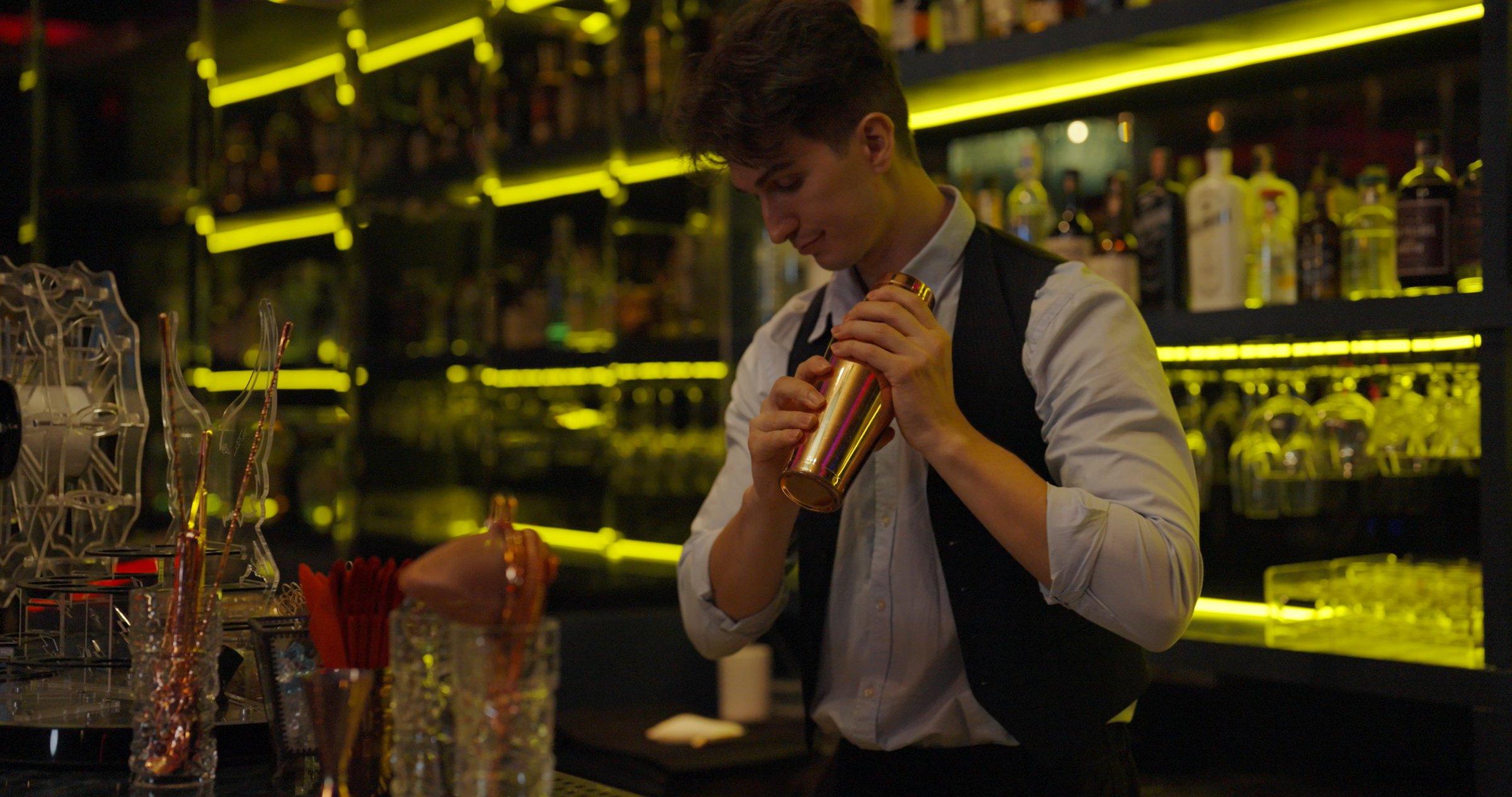 Celebration concept. Bartender mixing cocktails at the bar. He was shaking the ingredients together.