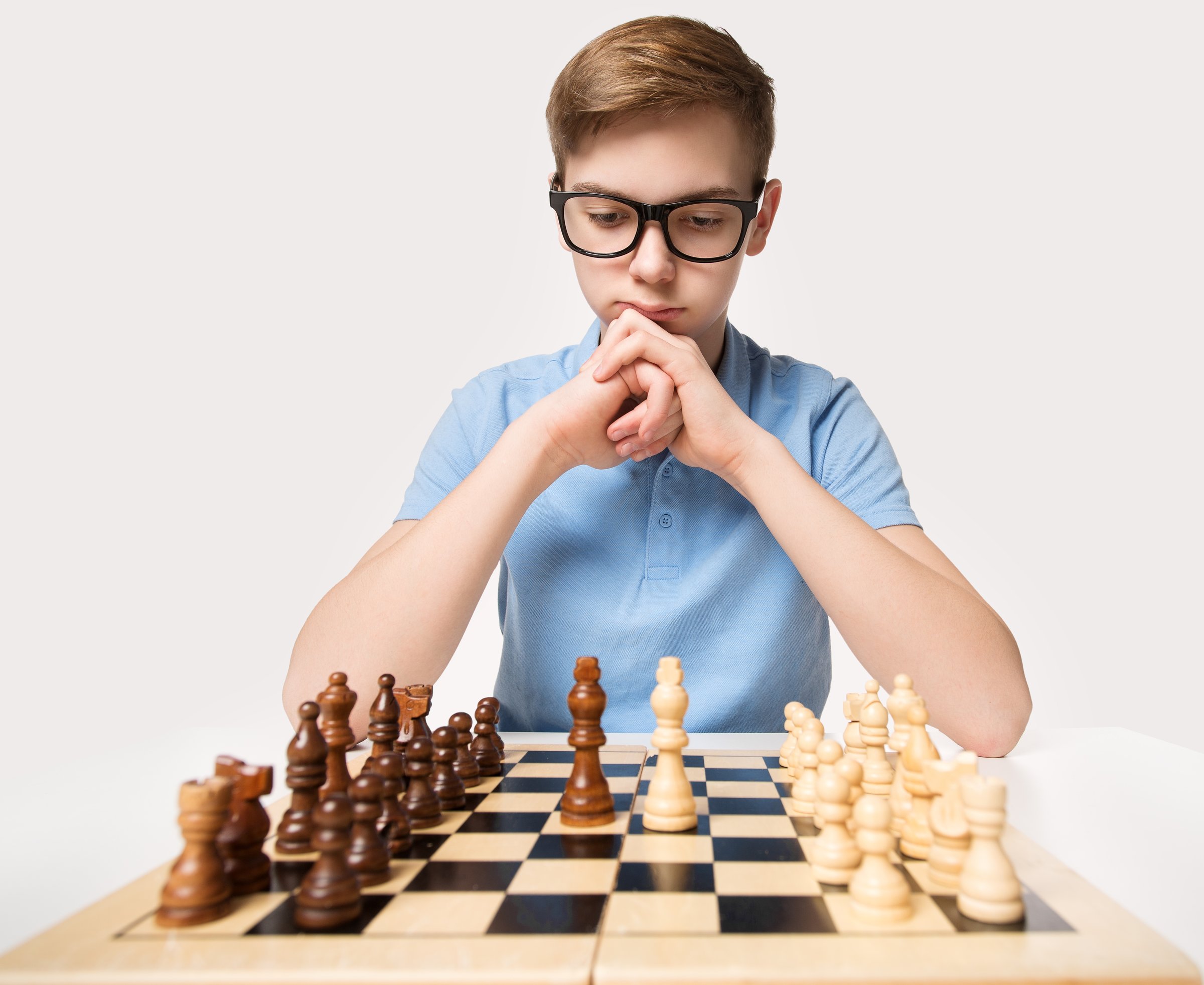 Intelligent Thoughtful Teenage Boy in Eyeglasses Playing Chess Game. Kid Learning Strategy Thinking. Child Education Concept over White Studio background