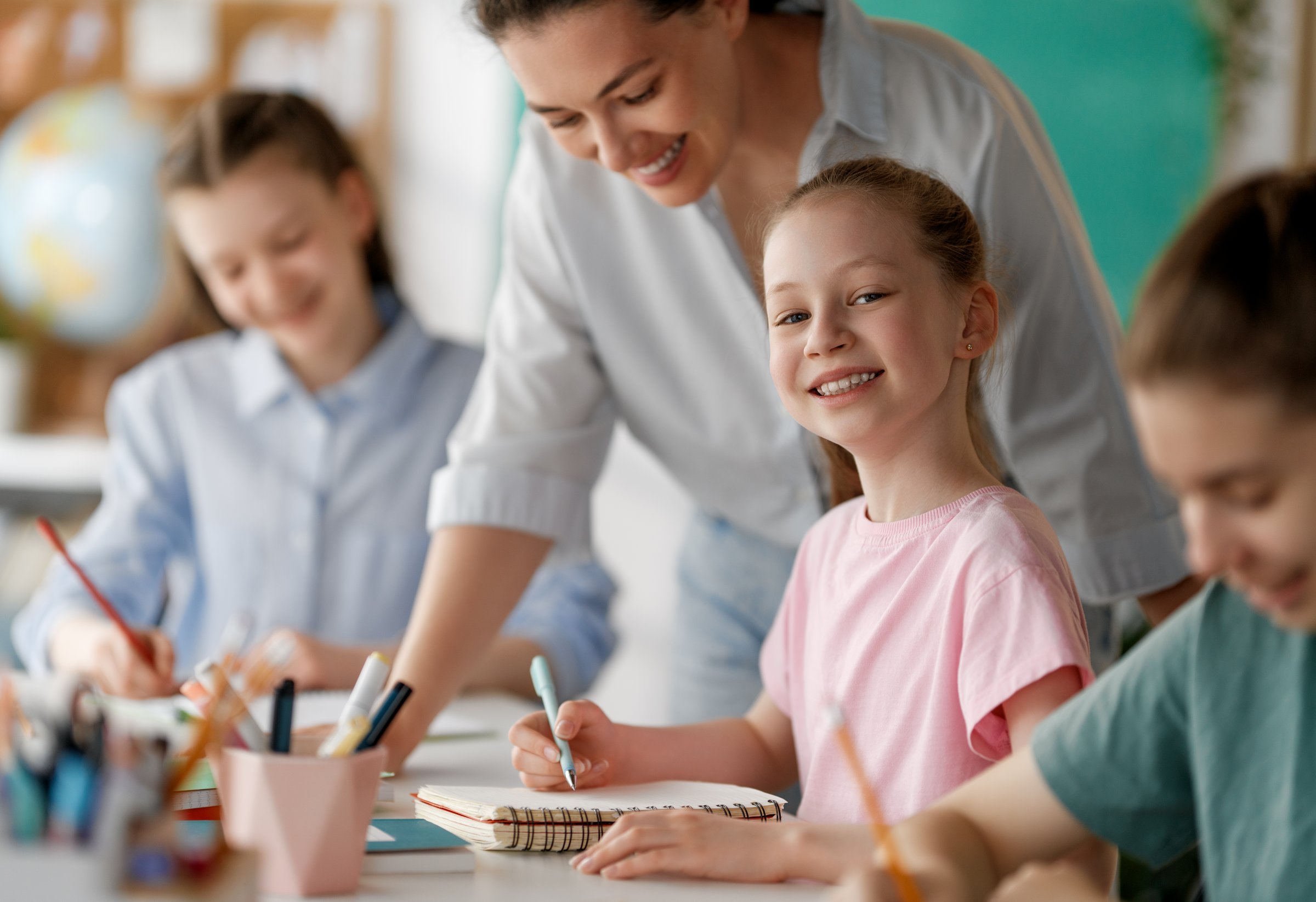 Happy kids and teacher at school. Woman and children are working in the class.