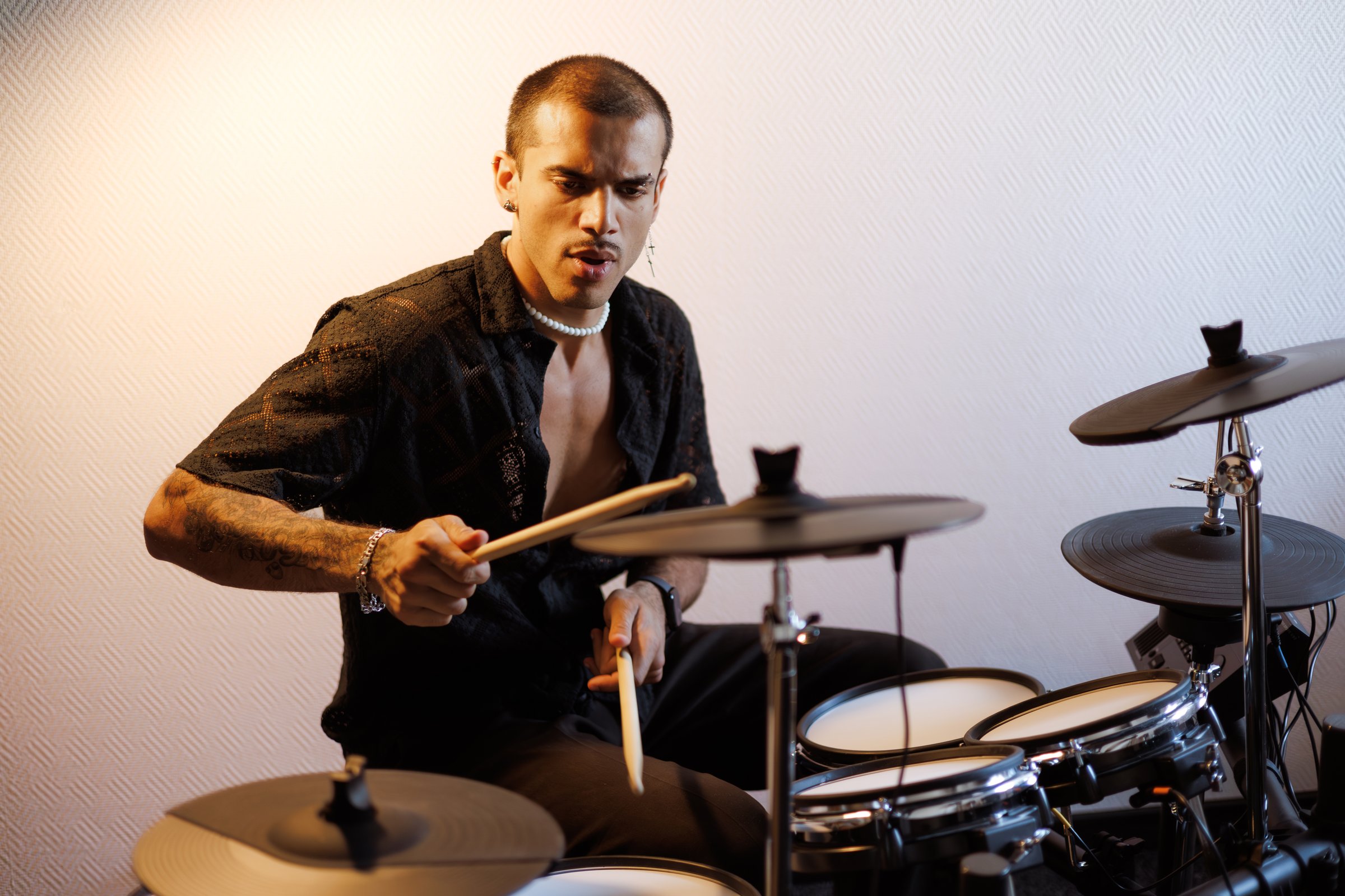 Focused mixed race performer playing drums in music studio