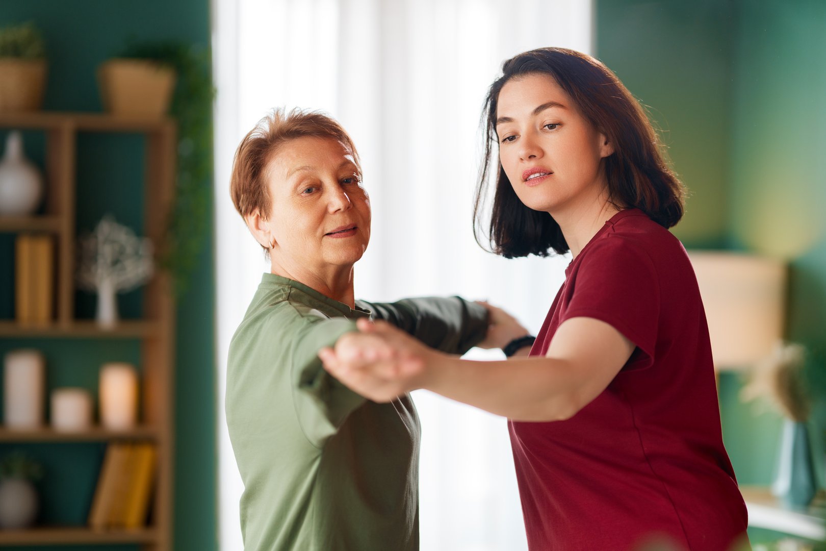 Senior woman doing exercise. A nurse helping with physical therapy at home