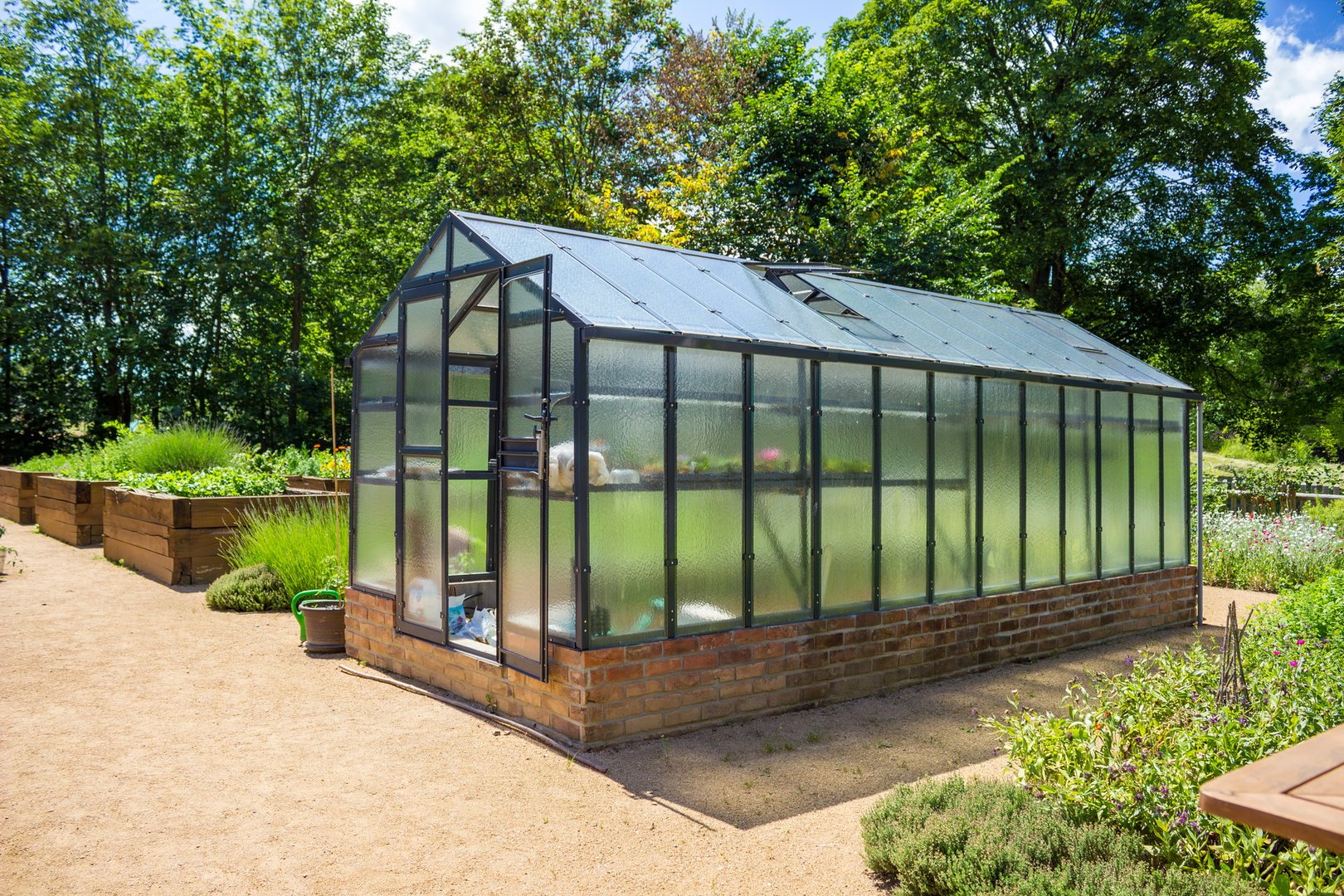 Traditional Metal and Glass Greenhouse in a Vegetable Garden. High quality photo