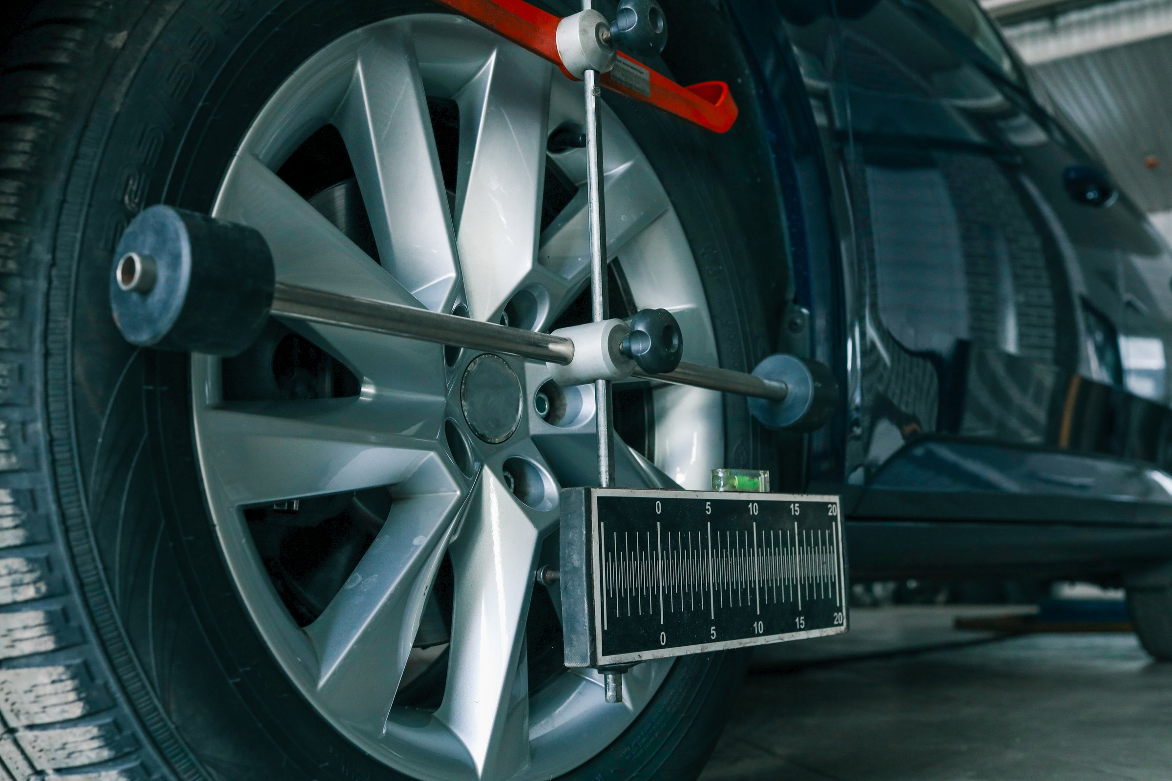 Close-up of a car wheel being measured for alignment using professional calibration equipment in an auto workshop.
