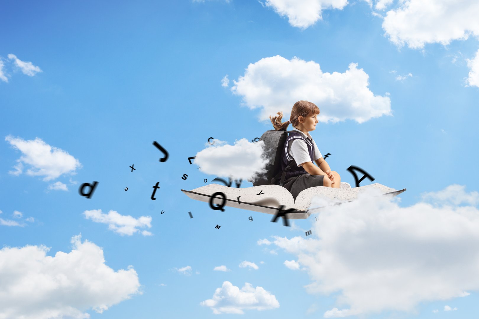 Schoolgirl sitting on a book and flying in the sky