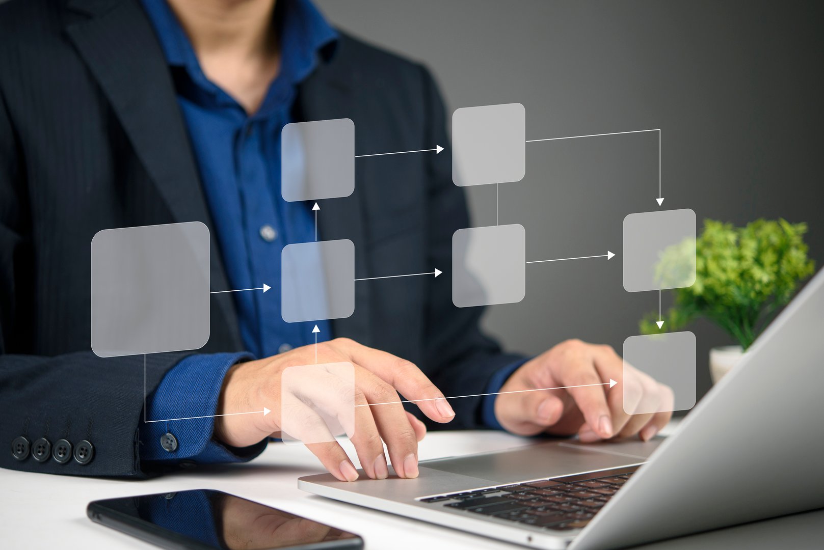 Business professional using a laptop to create a virtual flowchart, demonstrating digital technology for process organization and optimization.