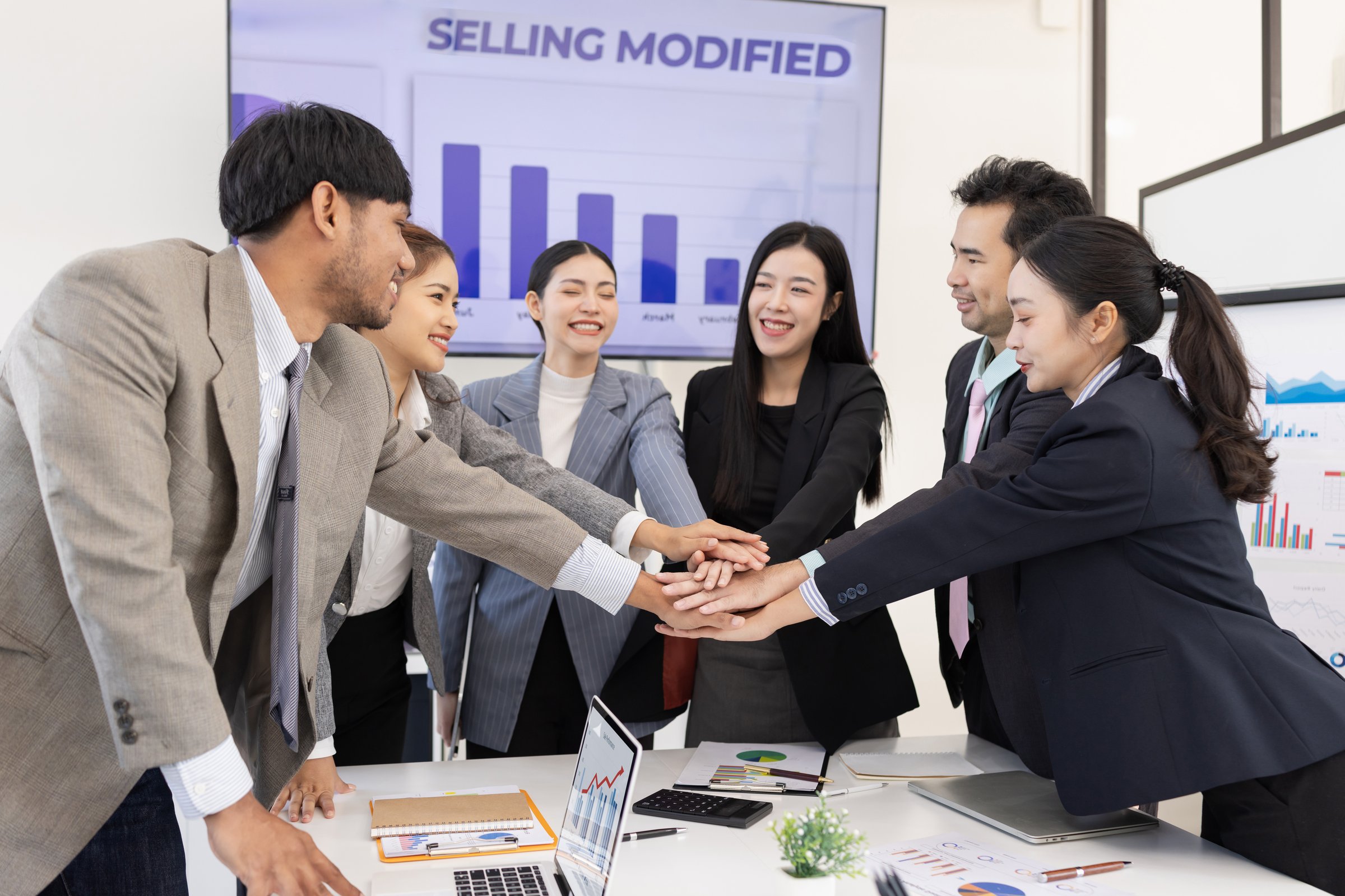 Group of Asian businesspeople Join hands and working together as a team in modern office, Business startup and company strategy planning concept.
