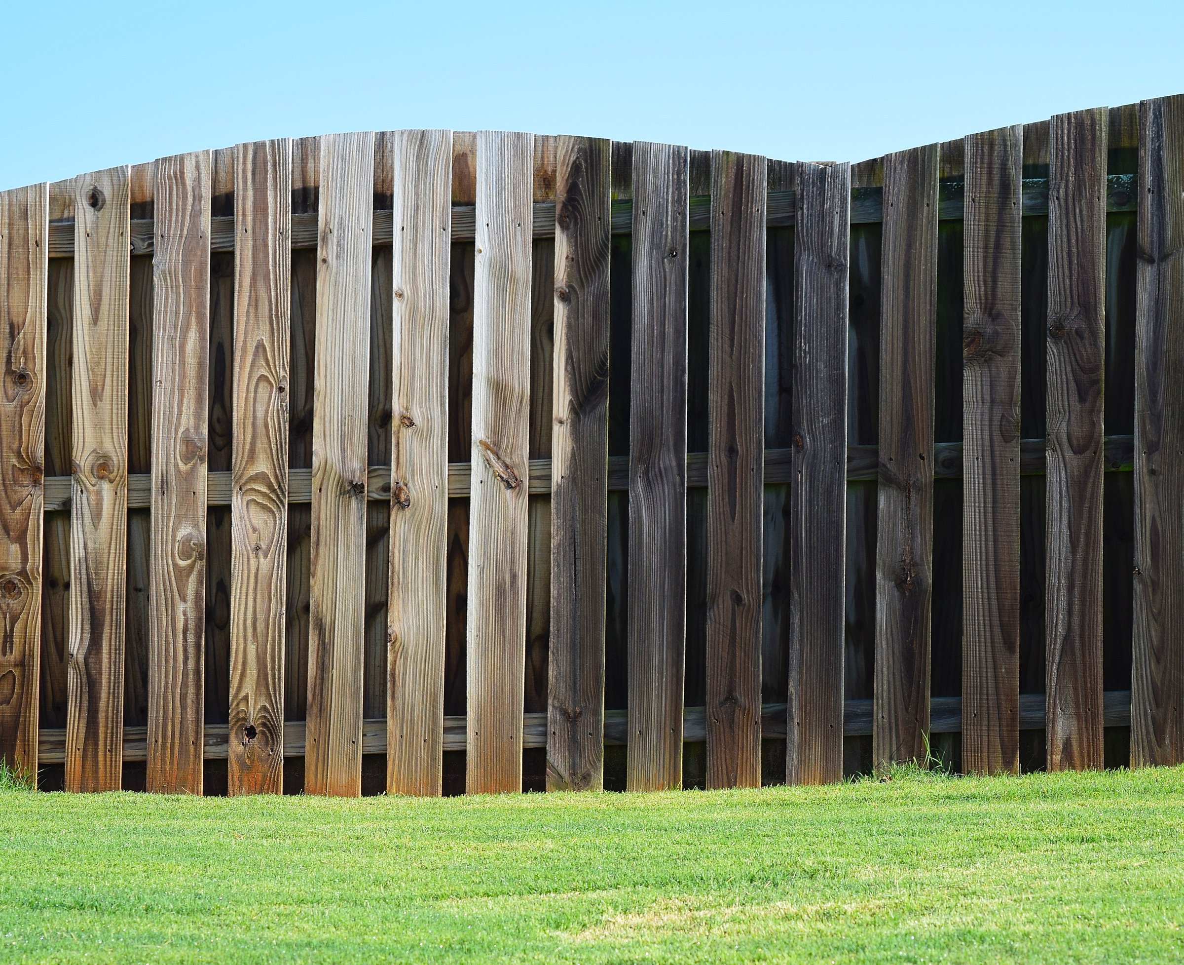 Picture showing how an aged wood property fence looks before and after a pressure washing