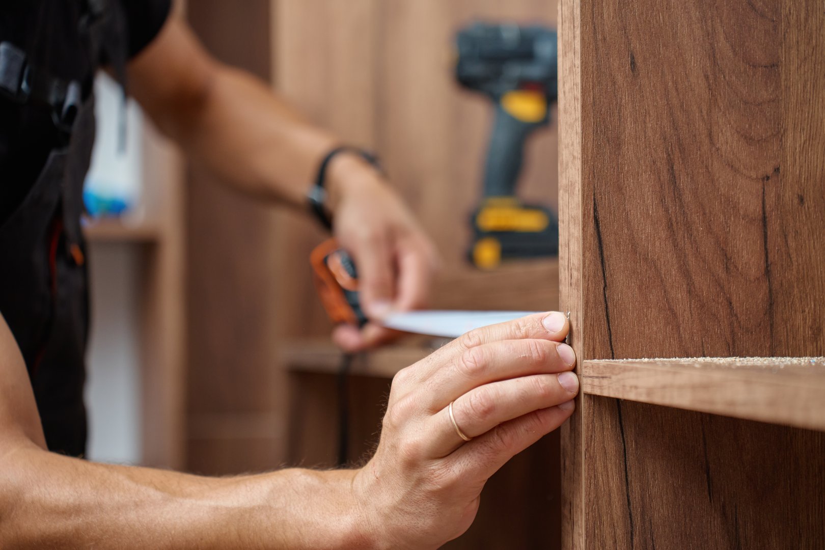 Close-up of man measuring wooden wardrobe with tape measure